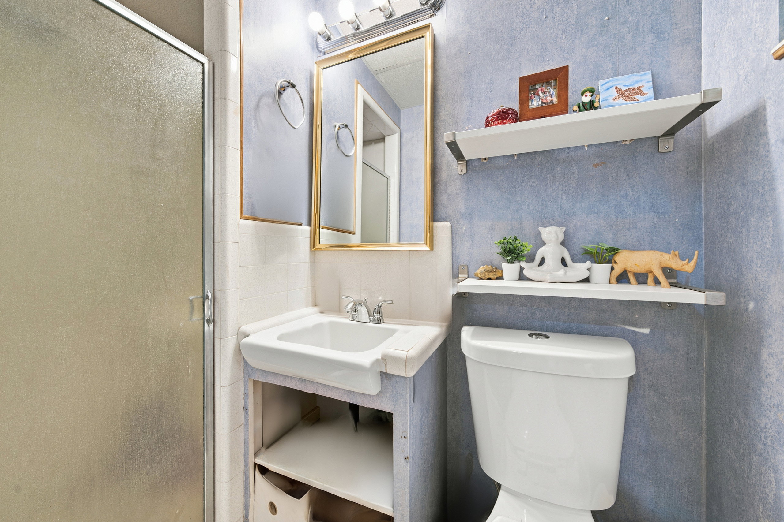 Bathroom featuring a built-in white vanity sink, a gold-framed wall mirror, and a chrome light fixture