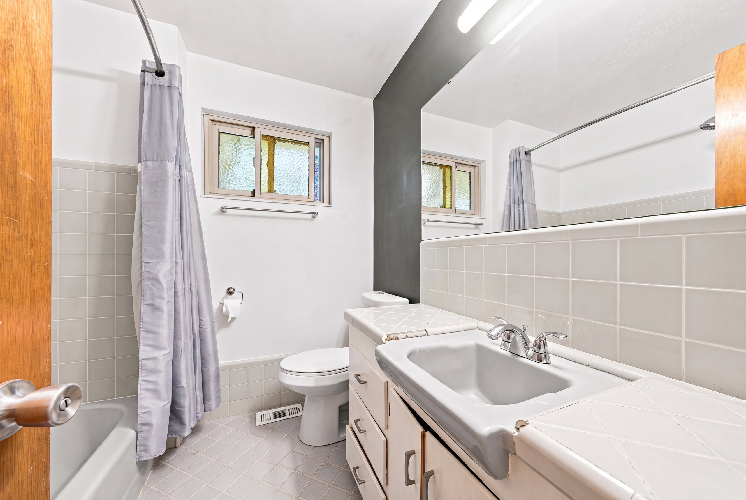 Bathroom featuring a white vanity with integrated sink, chrome faucet, and tiled countertop