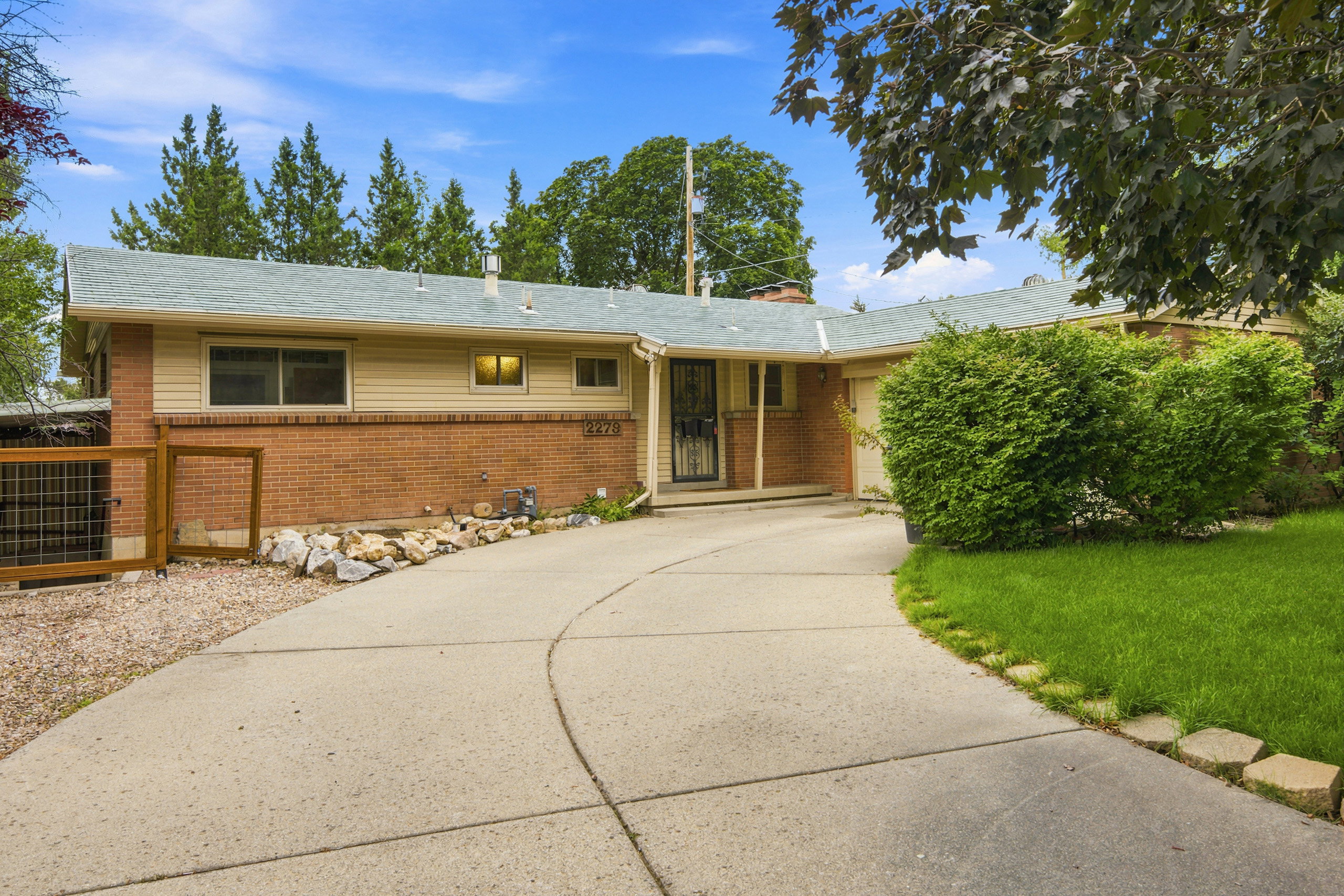 Ranch-style residence featuring a brick and siding exterior, a light-colored shingle roof, and a curved concrete driveway