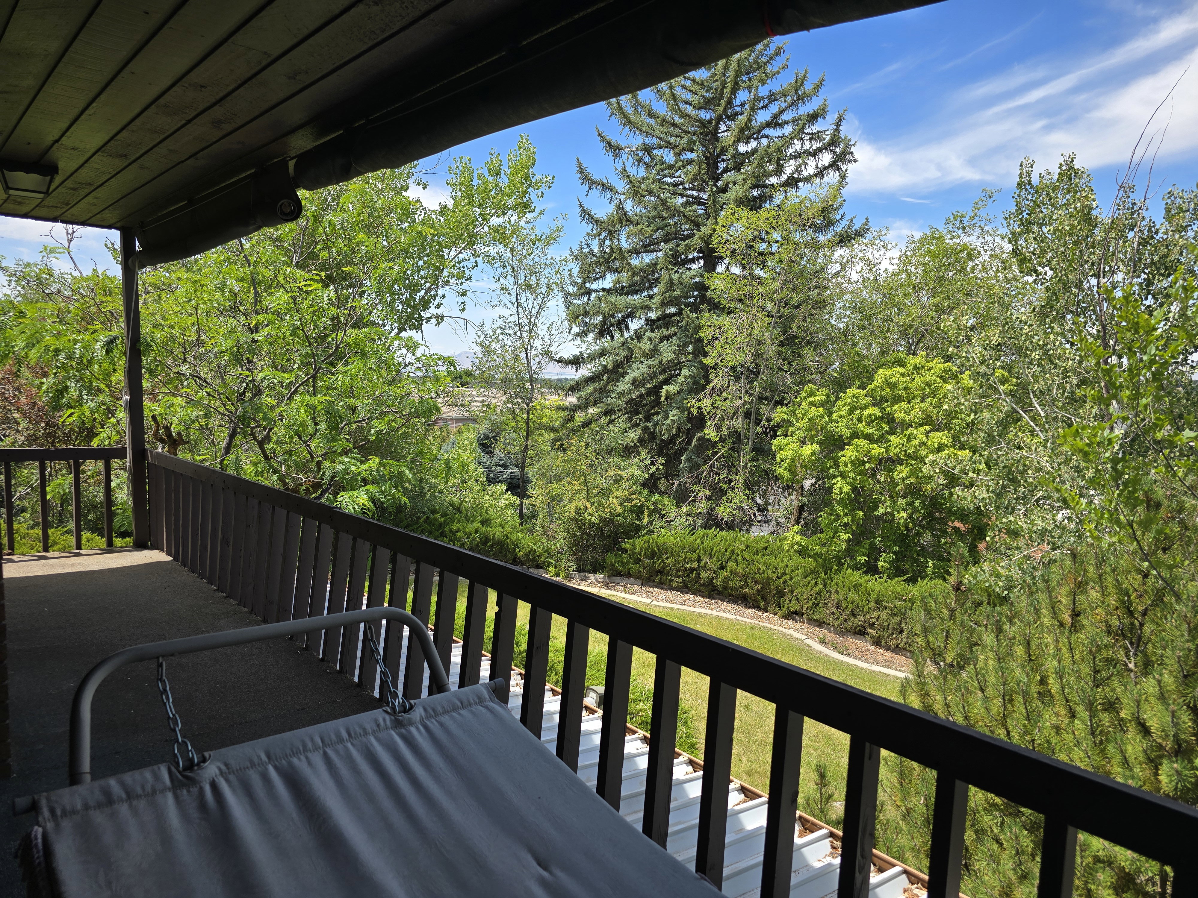 Covered outdoor deck with dark wood-finish ceiling, dark wood-finish railings, and a dark floor surface