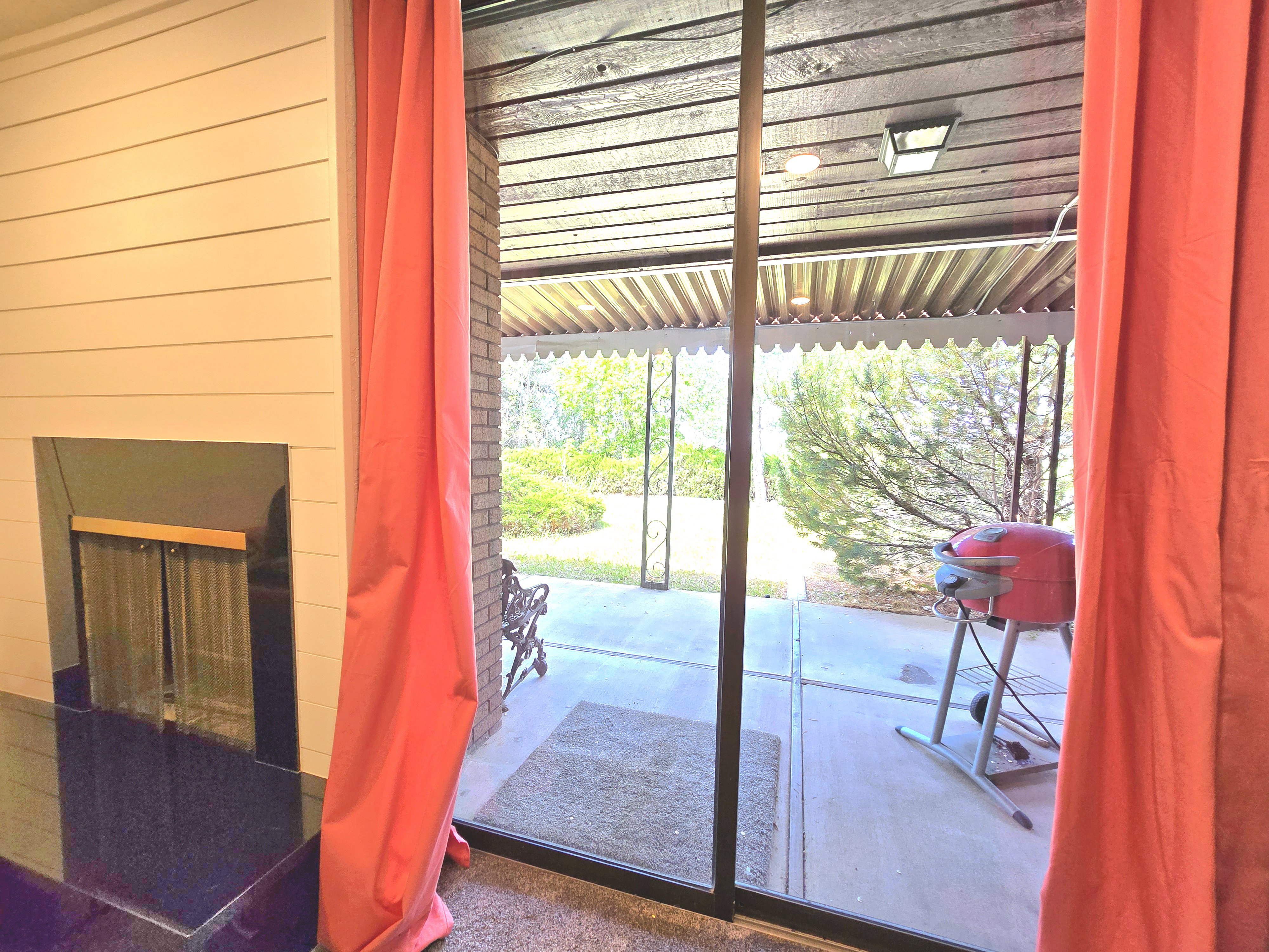 Sliding glass door opening to a covered patio featuring a wood-plank ceiling and brick-patterned wall