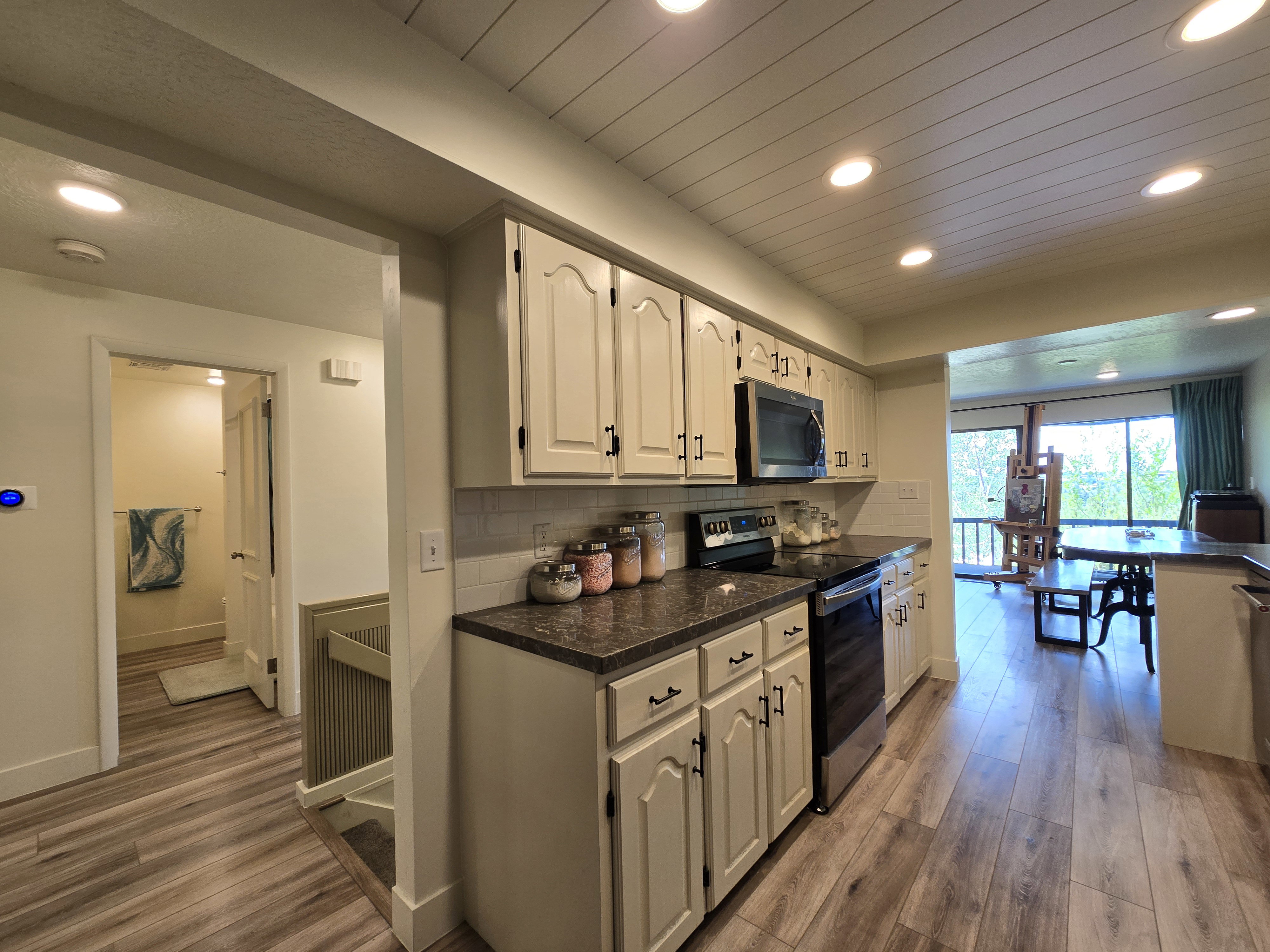 Functional kitchen featuring cream cabinetry with dark hardware, a subway tile backsplash, and dark countertops
