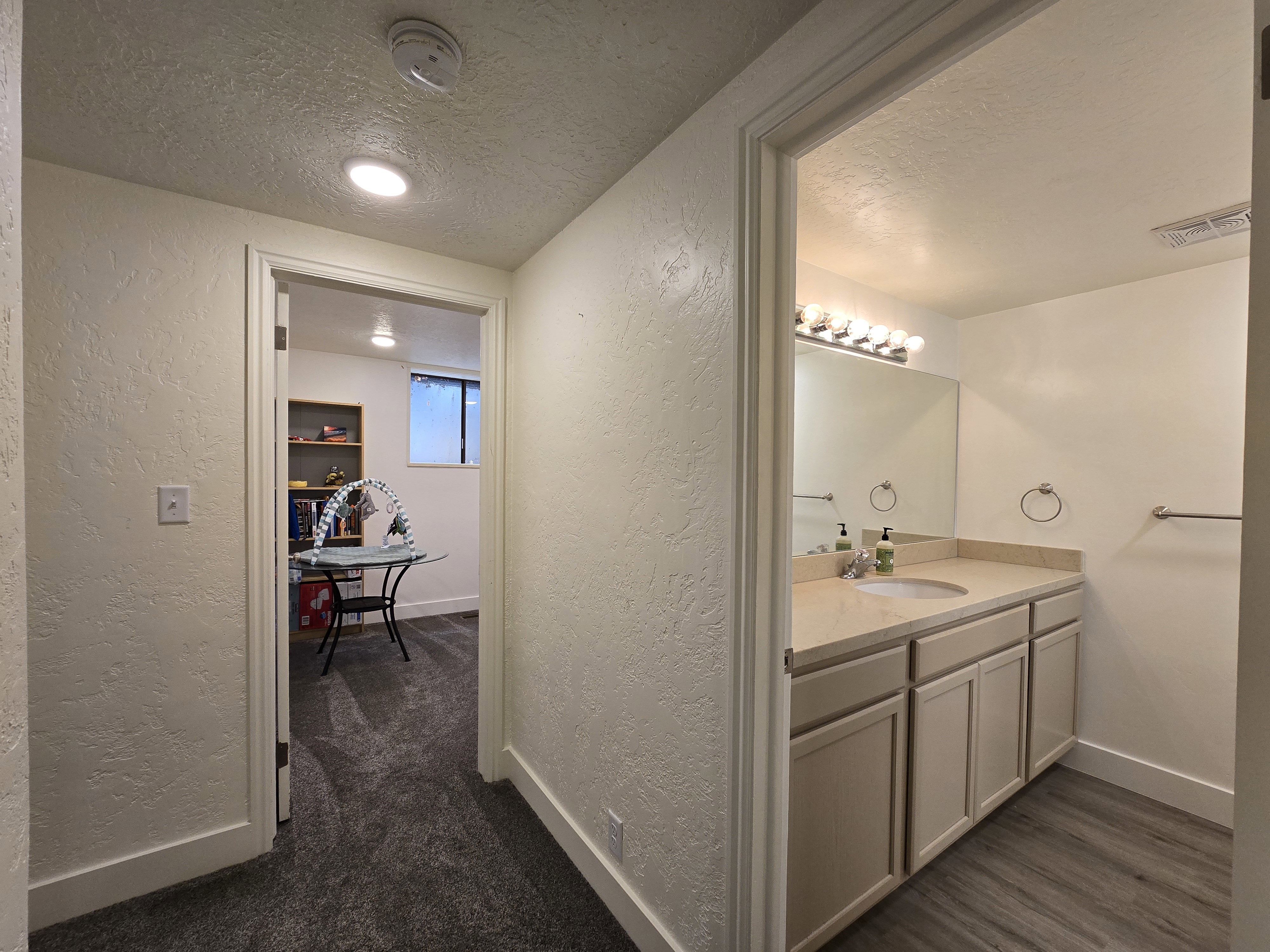 Bathroom featuring a single vanity with light-toned cabinetry, a built-in sink, and a large wall-mounted mirror