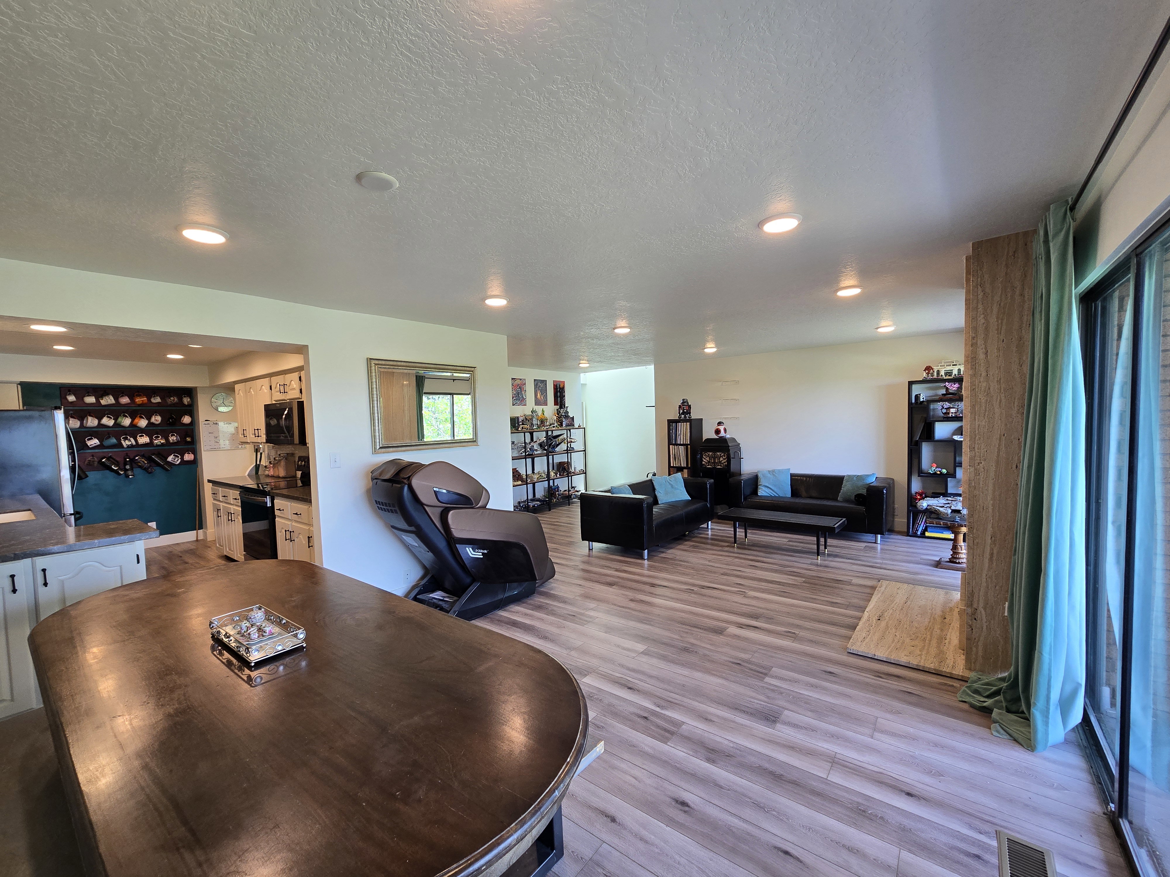 Open-concept living space featuring wood-finish flooring, recessed lighting, and a kitchen with white cabinetry and dark countertops