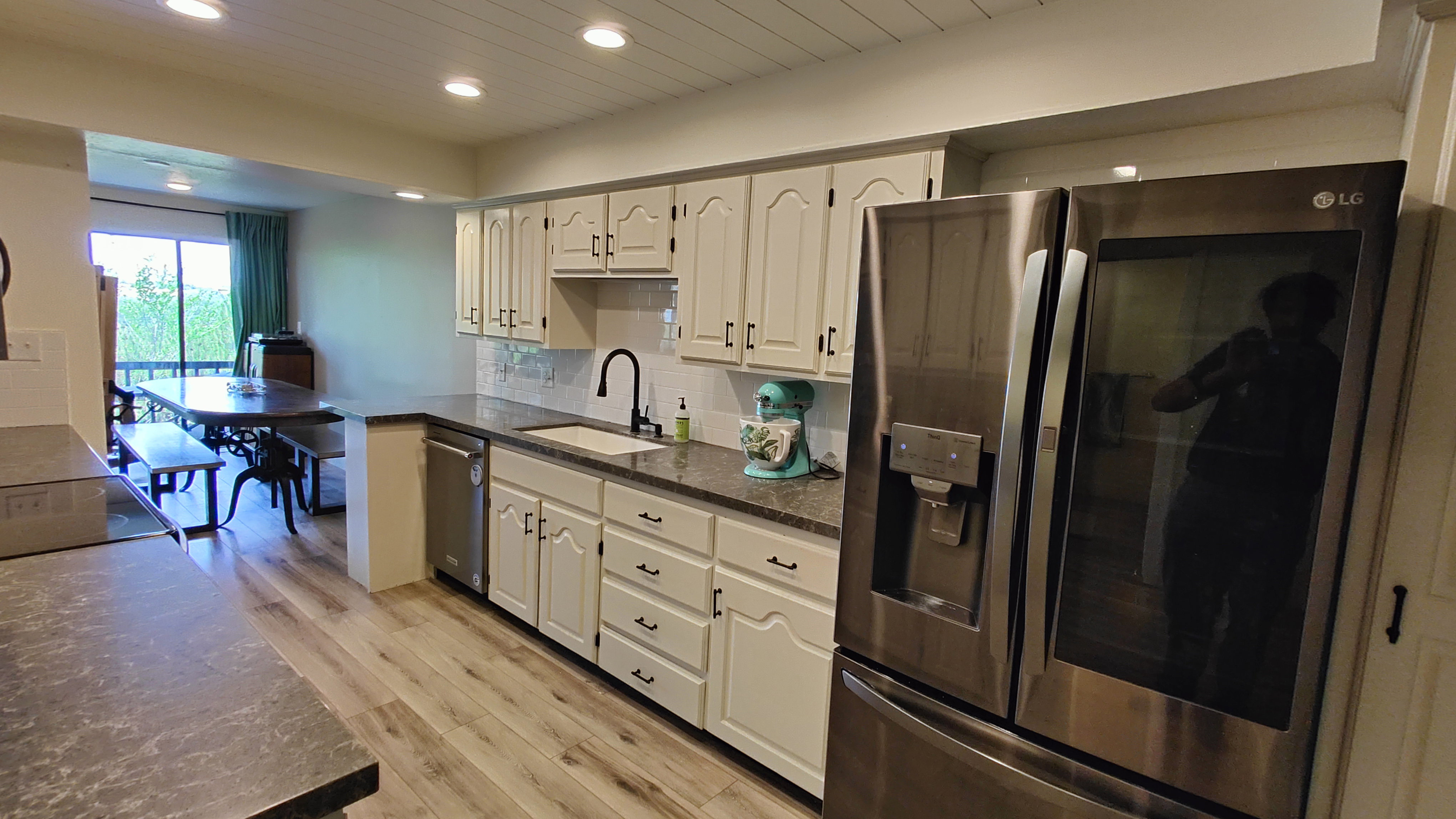 Kitchen featuring wood-finish flooring, white cabinetry, granite-style countertops, a stainless steel refrigerator, and a stainless steel dishwasher