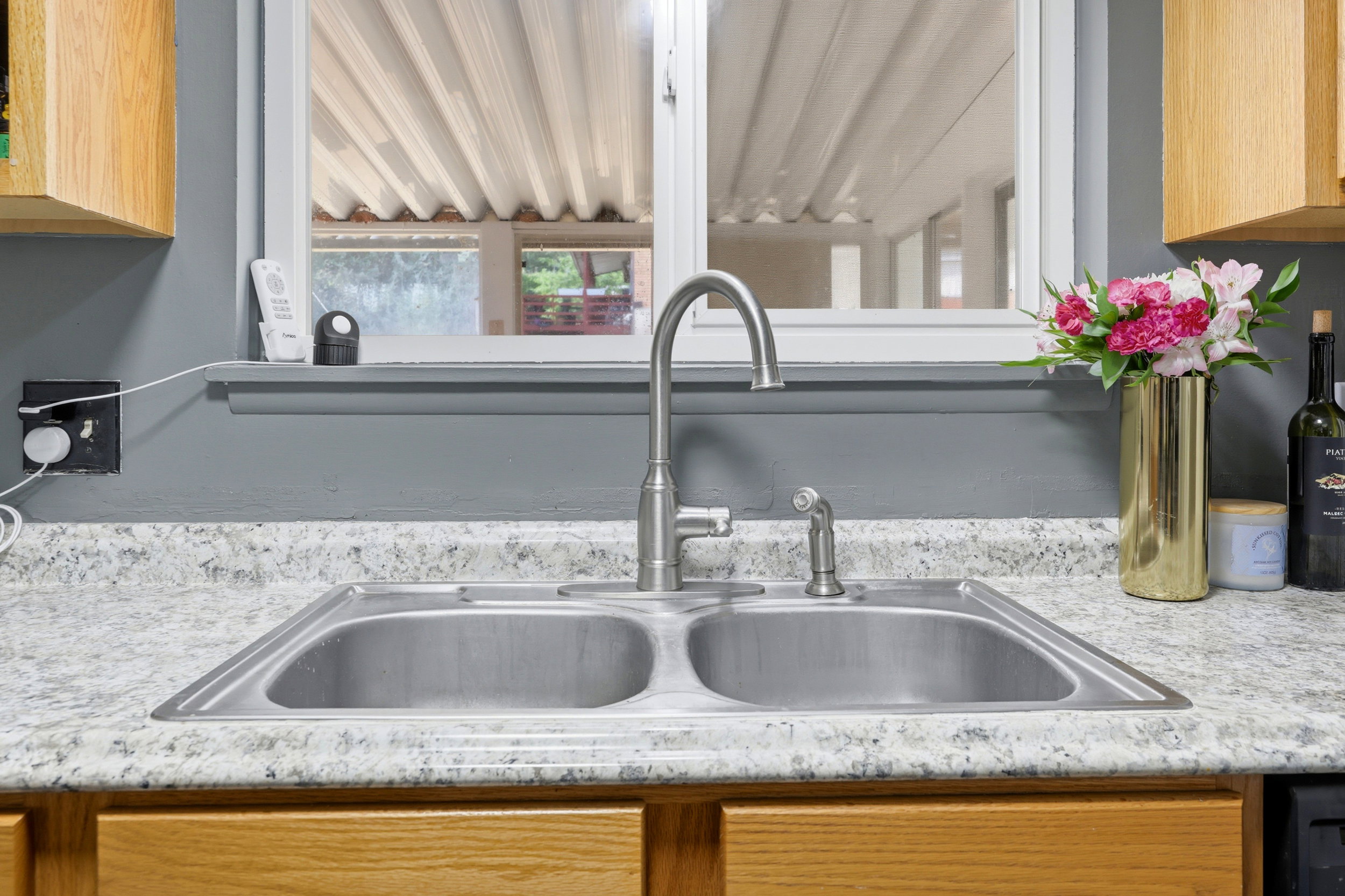 Double basin stainless steel sink with a high-arc faucet, set within a speckled countertop