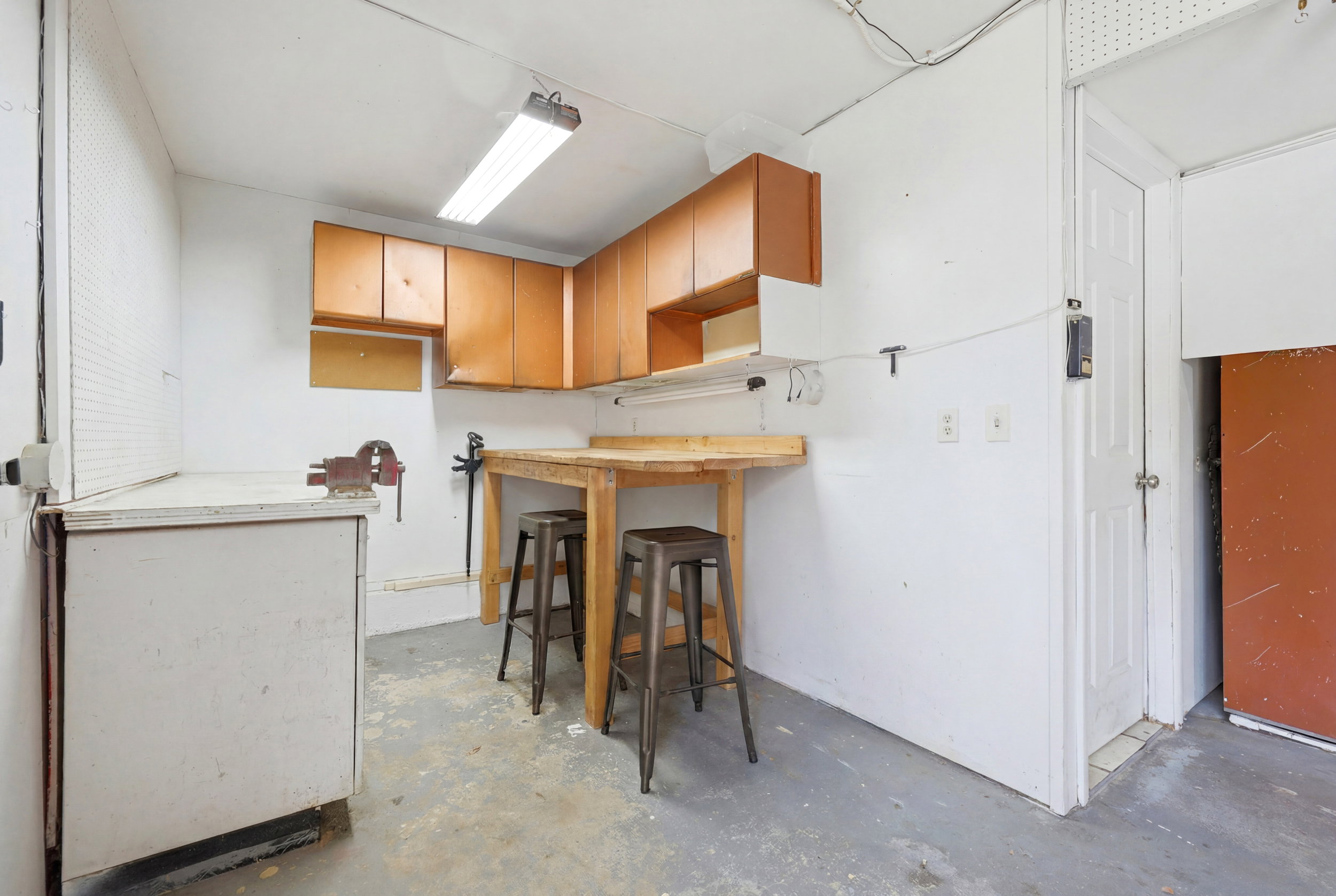 Dedicated workspace featuring wood-finish upper cabinetry, a built-in wood-finish workbench, and a white lower cabinet