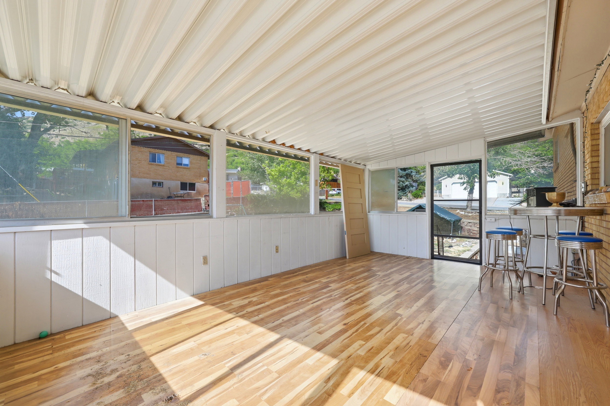 Enclosed sunroom featuring a paneled ceiling, wood-finish flooring, and white wainscoting