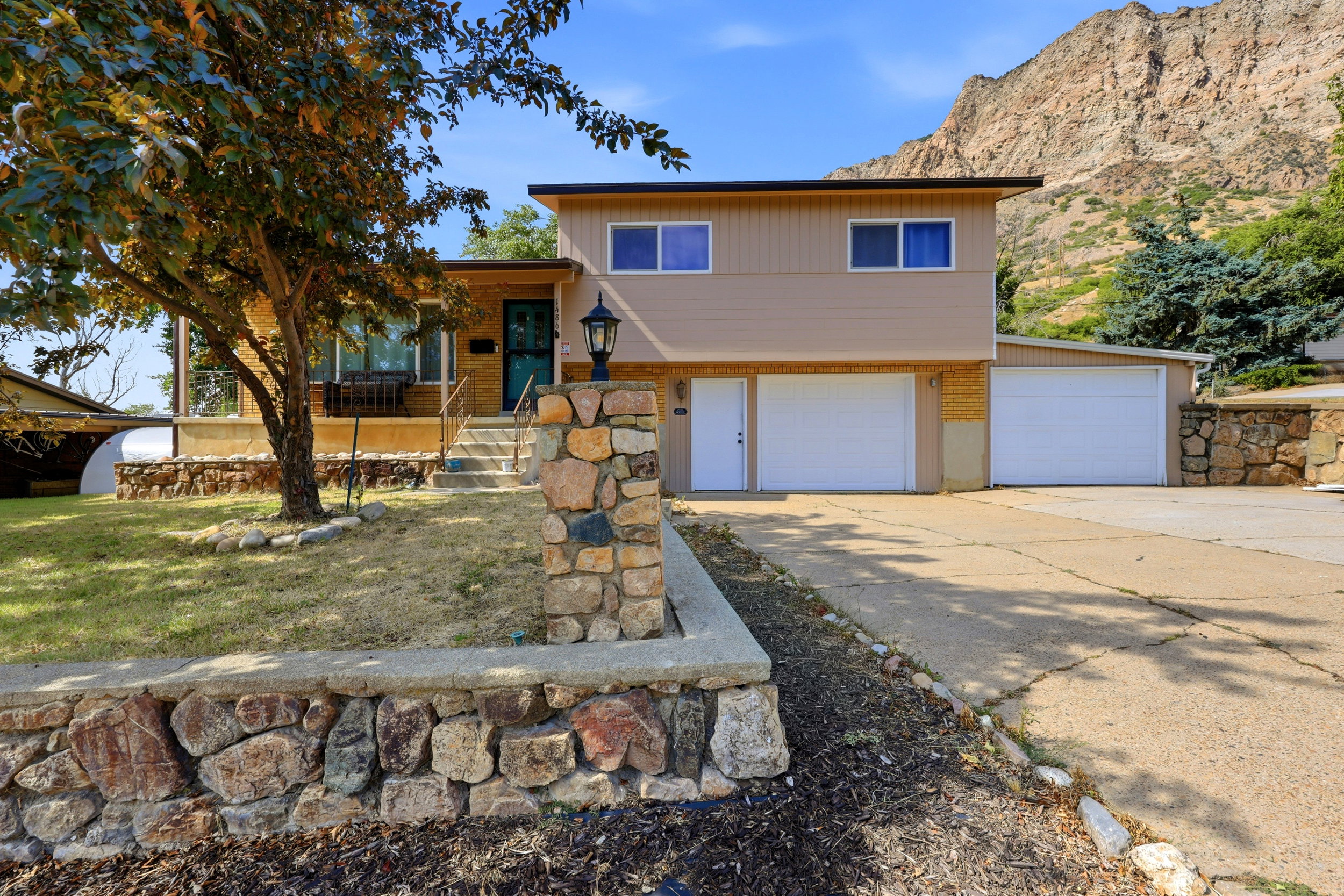 Split-level residence featuring a tan exterior and a prominent mountain backdrop