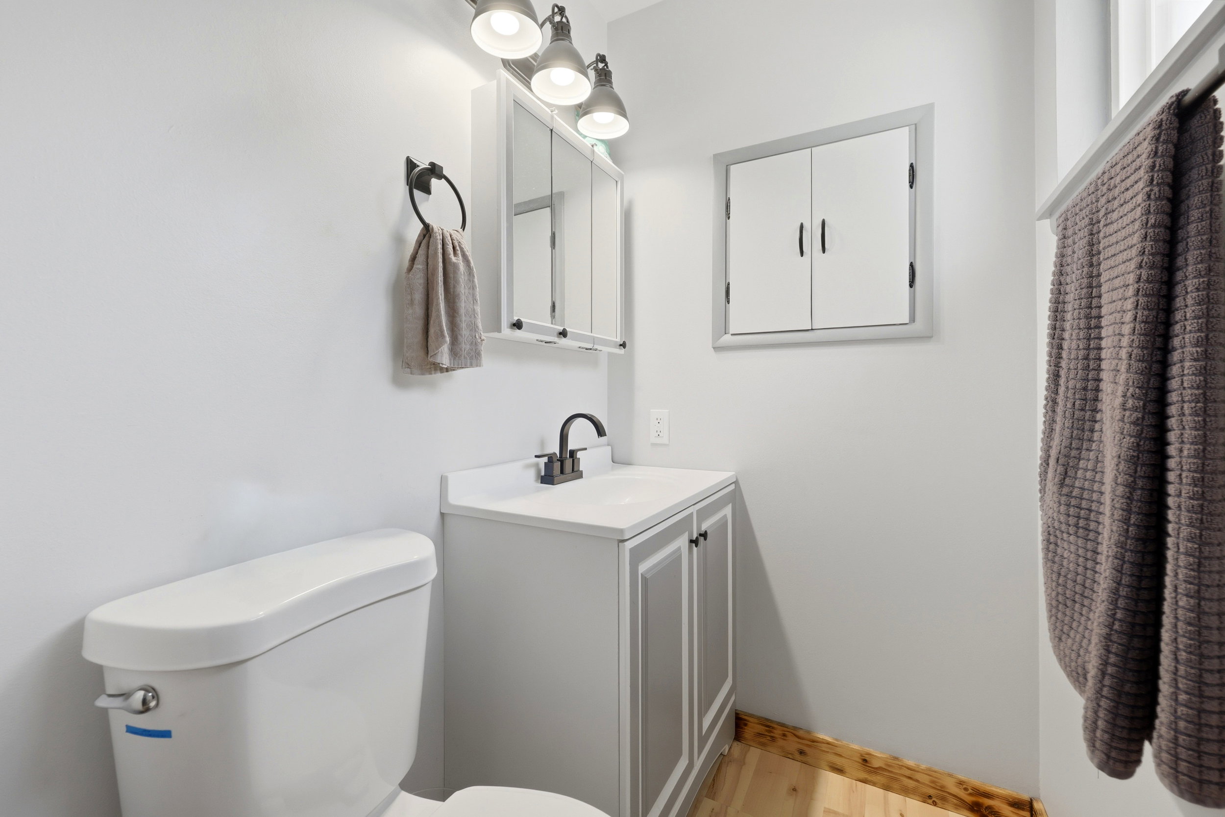 Bathroom featuring a white toilet, light gray vanity with white countertop, and a built-in medicine cabinet with a mirror