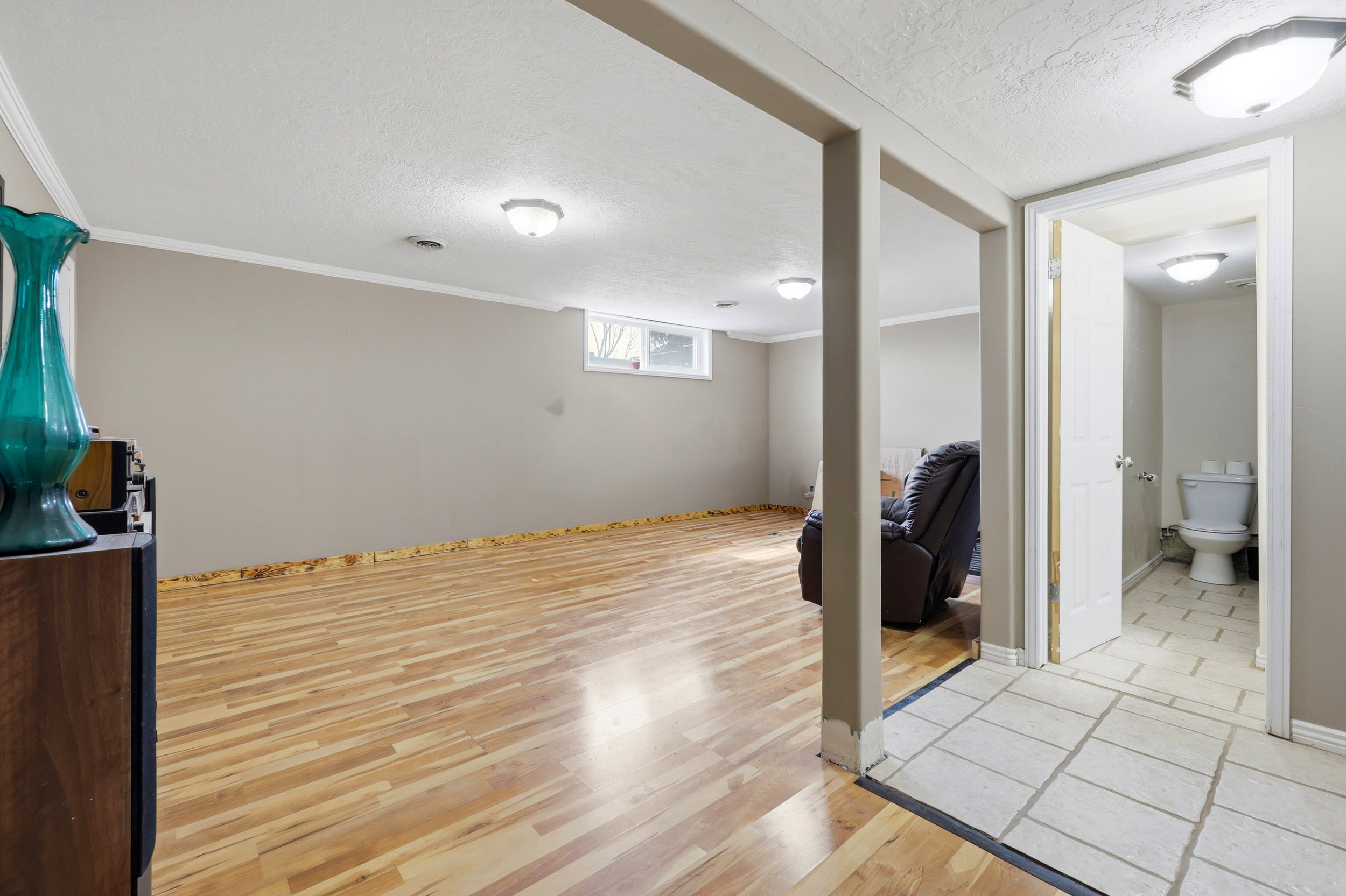 Lower-level living area featuring wood-finish flooring, recessed lighting, and a window