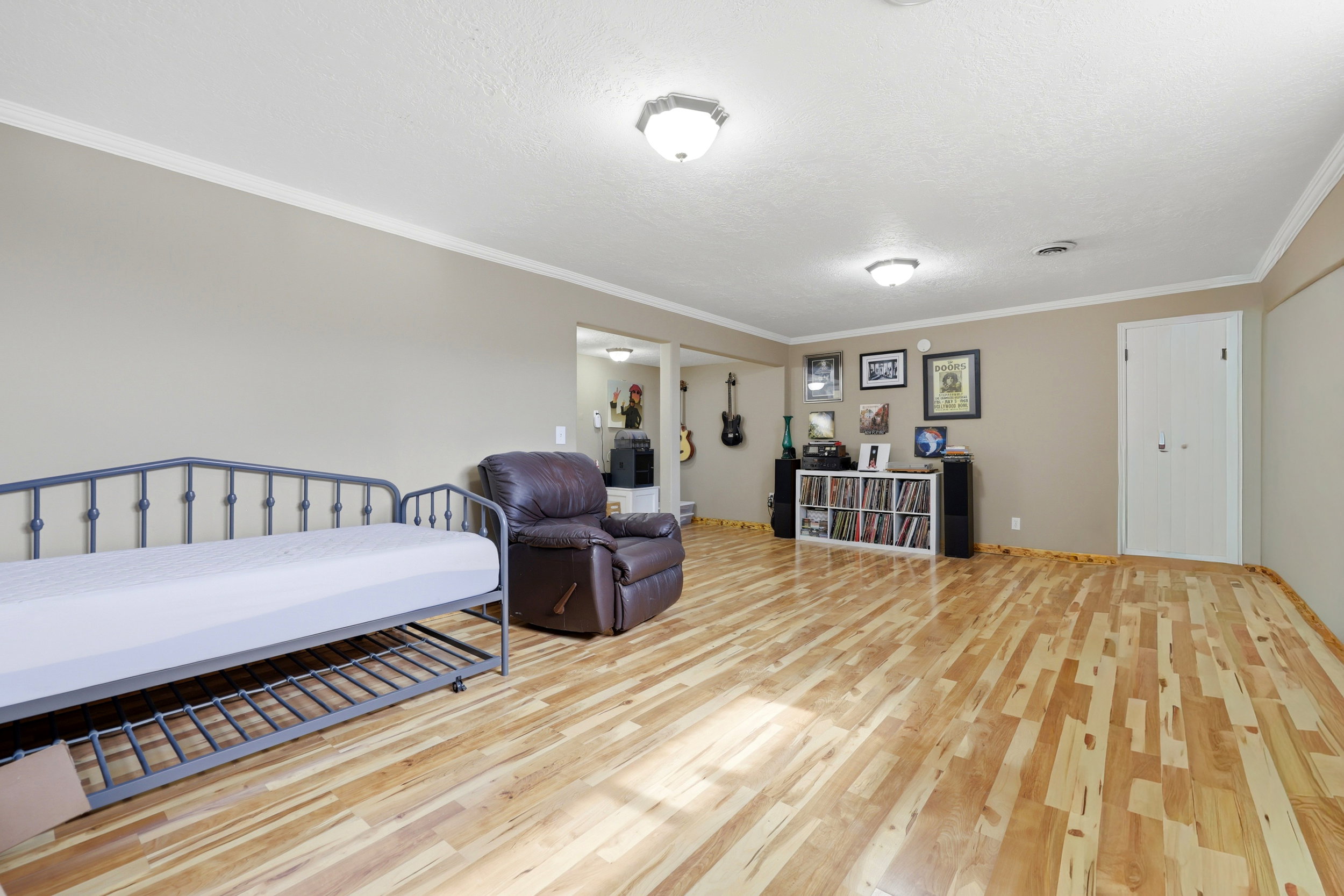 Bright living space featuring natural wood-finish flooring, neutral wall paint, and white crown molding