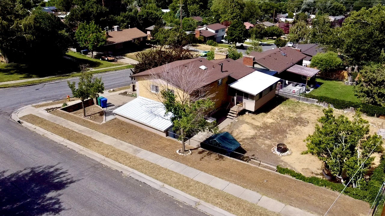 Corner lot property featuring a covered patio, extensive backyard space, and mature trees