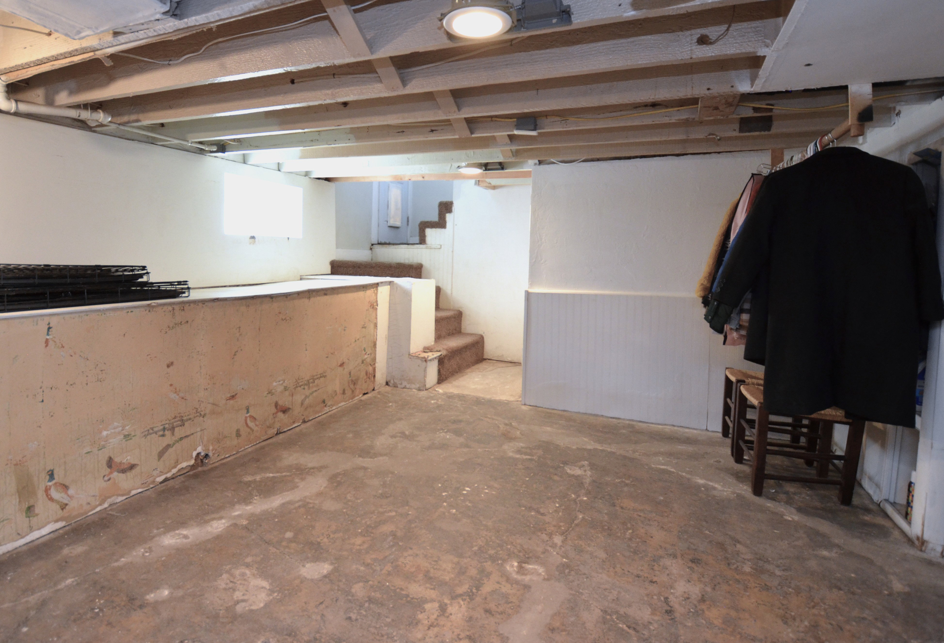 Unfinished lower level featuring exposed ceiling joists, concrete flooring, and a partial wall structure