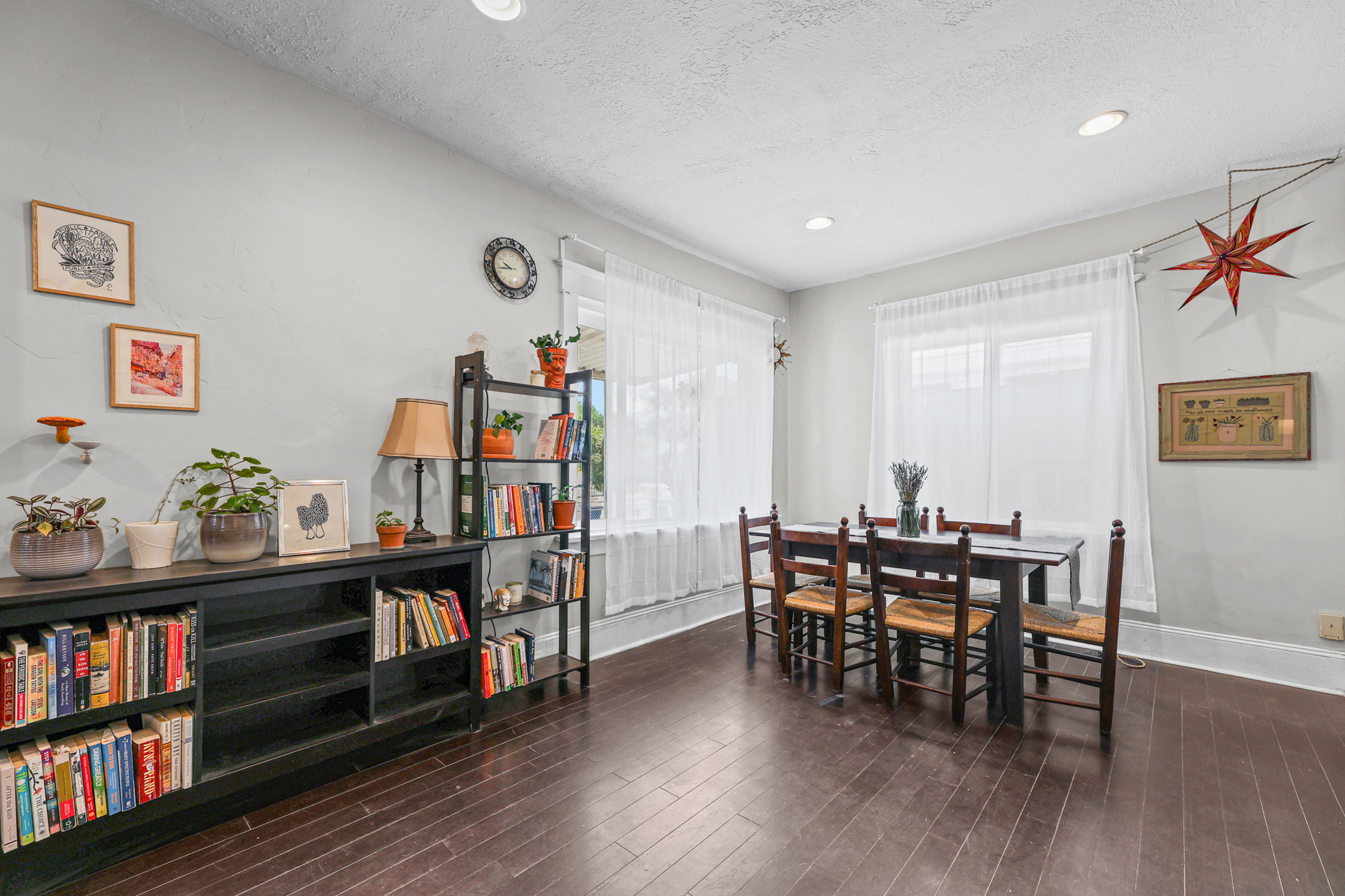 Spacious room featuring rich wood-finish flooring, recessed ceiling lighting, and multiple windows with sheer drapery