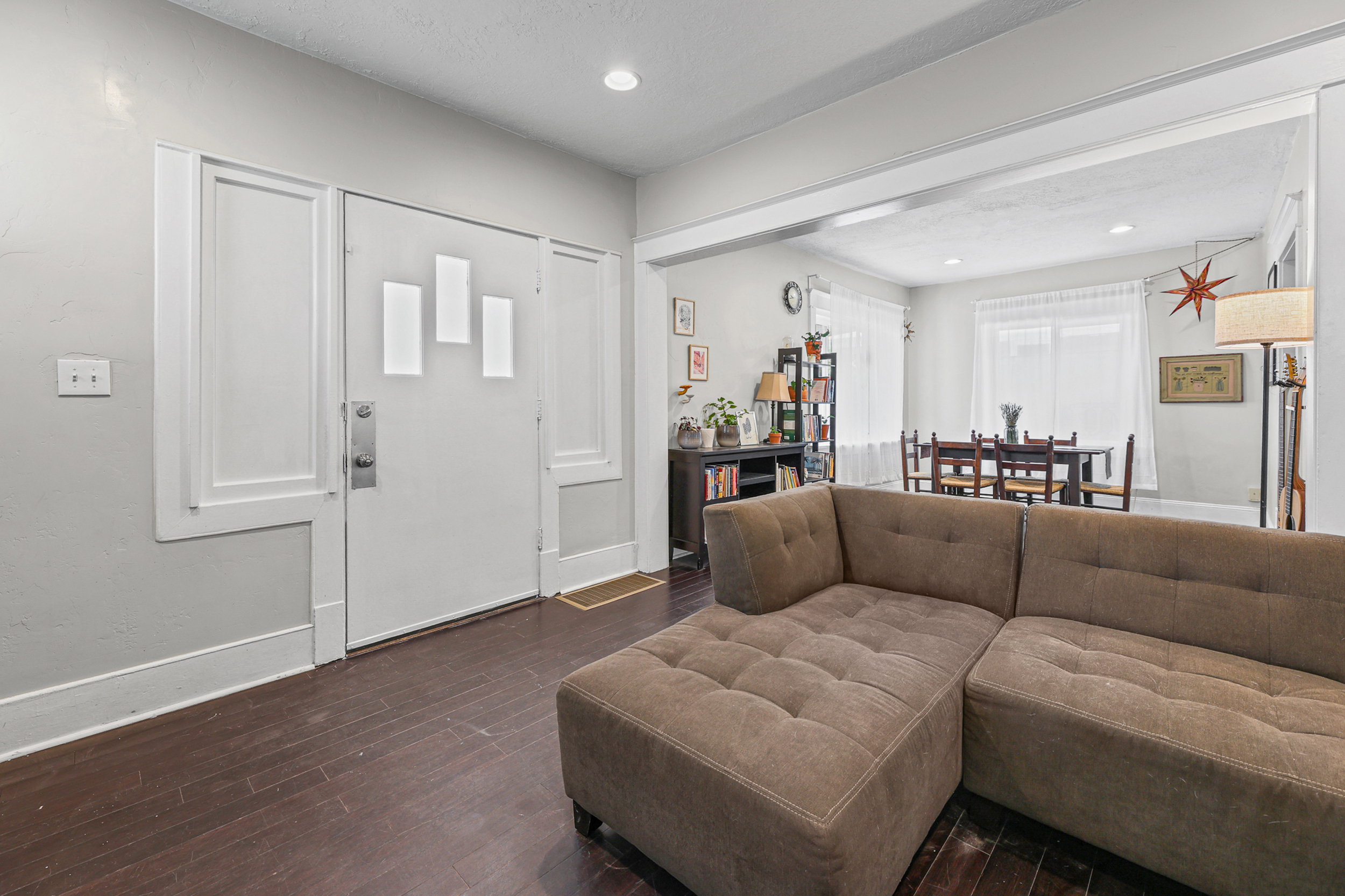 Entryway featuring a white door with decorative trim and sidelights, dark wood-finish flooring, and light-toned walls