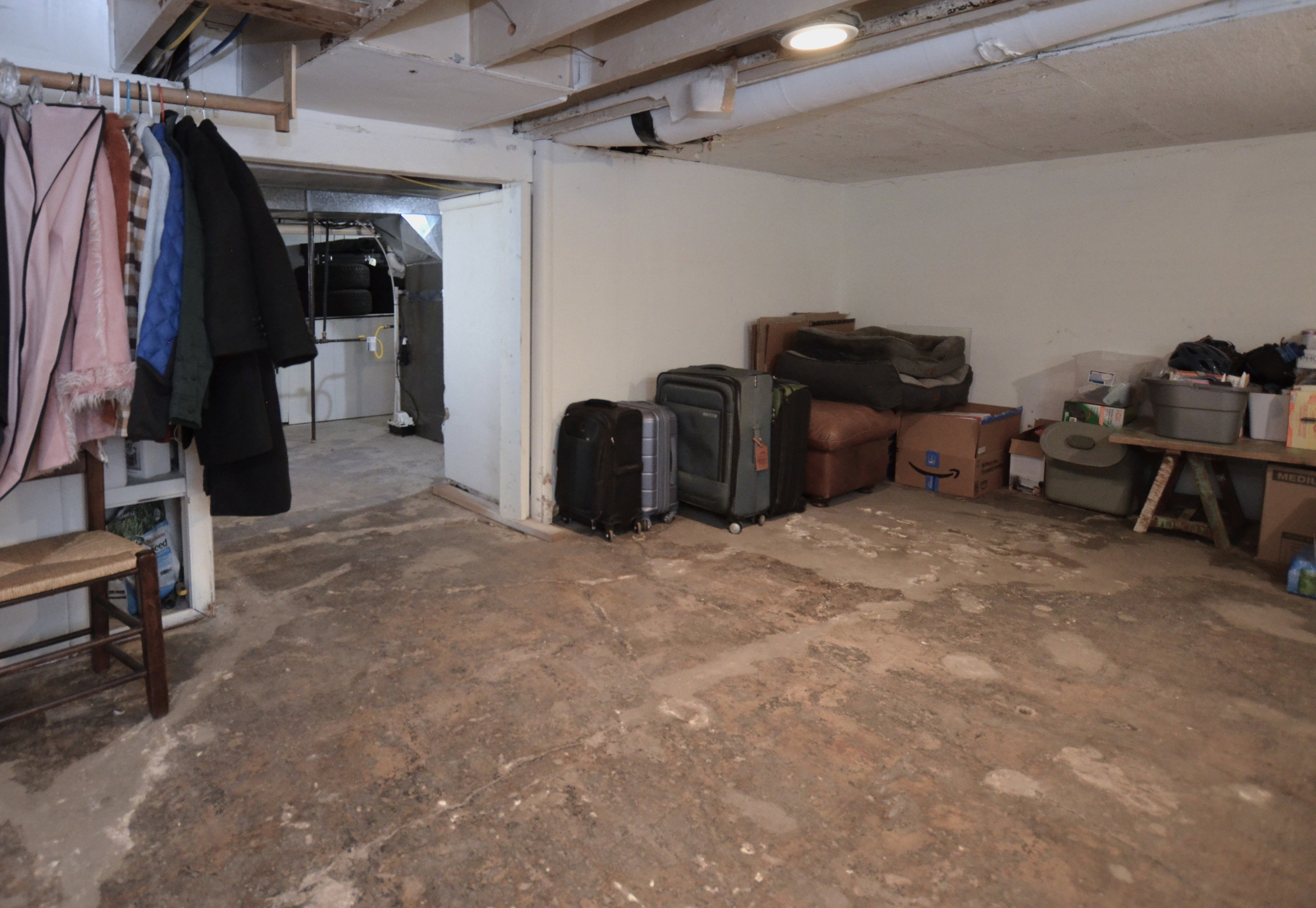 Concrete flooring with exposed ceiling joists and a painted white wall