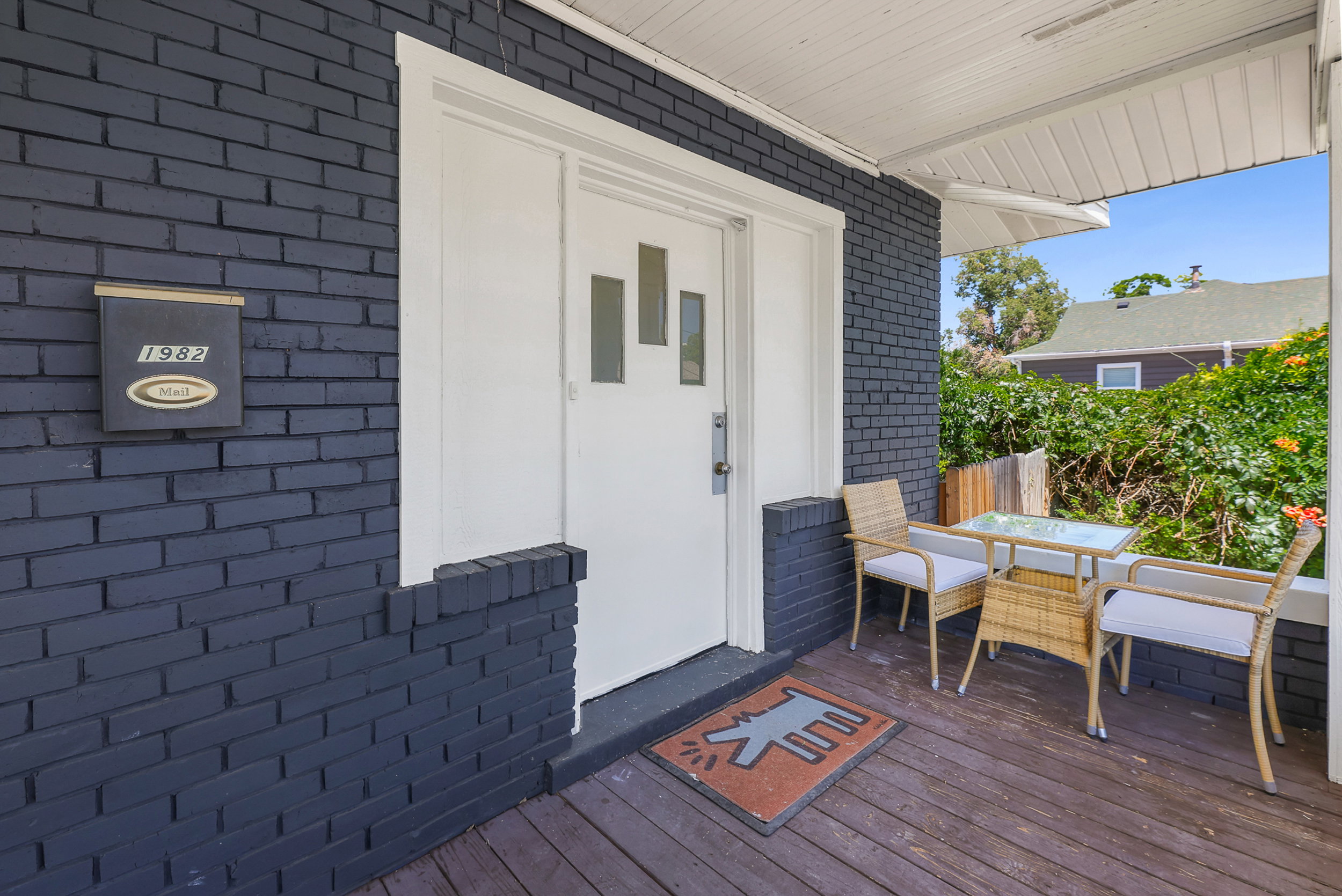 Covered front porch with dark-stained wood flooring and painted brick wall