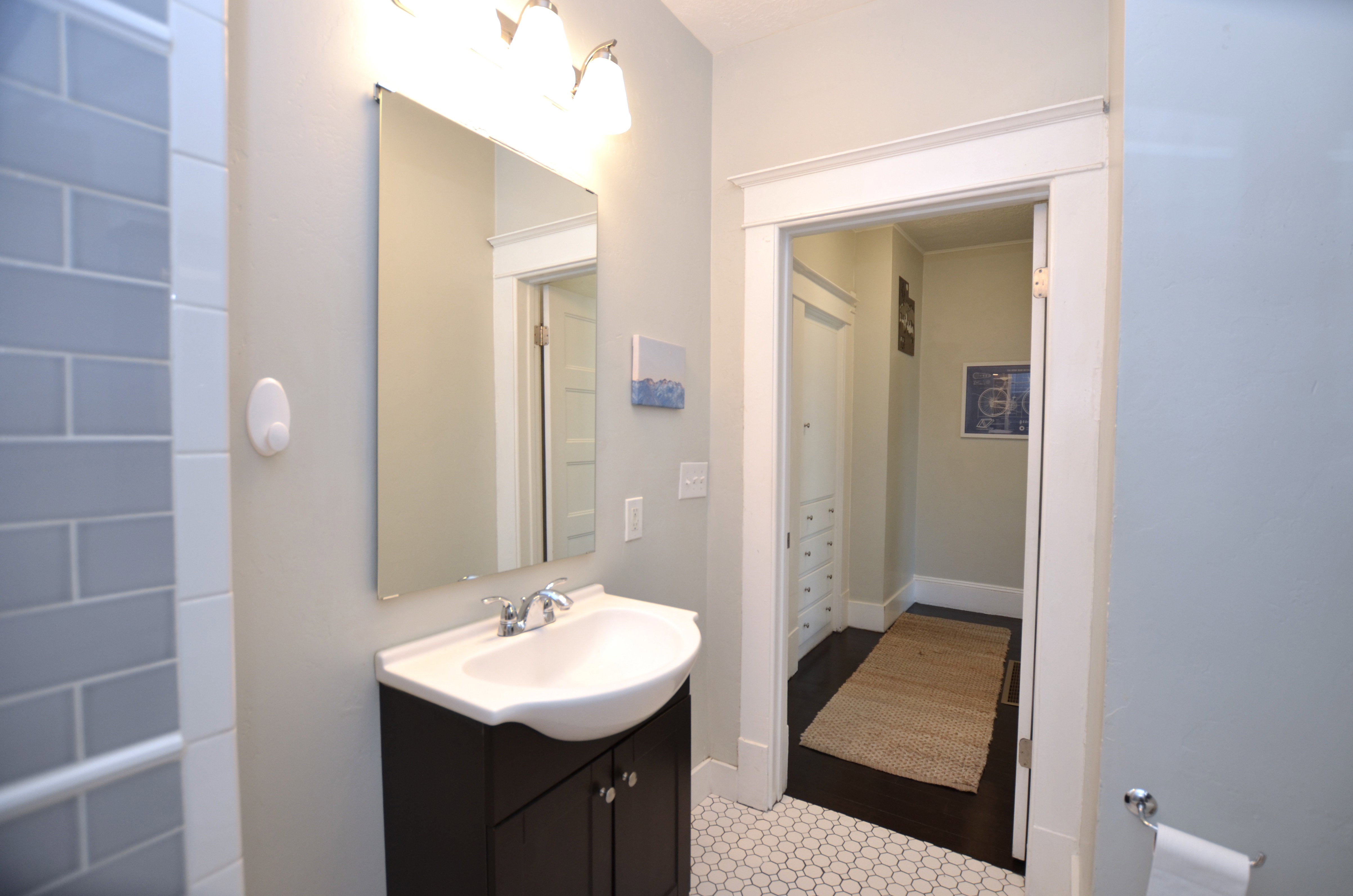 Bathroom featuring a dark wood vanity with a white basin sink, chrome faucet, and a wall-mounted rectangular mirror