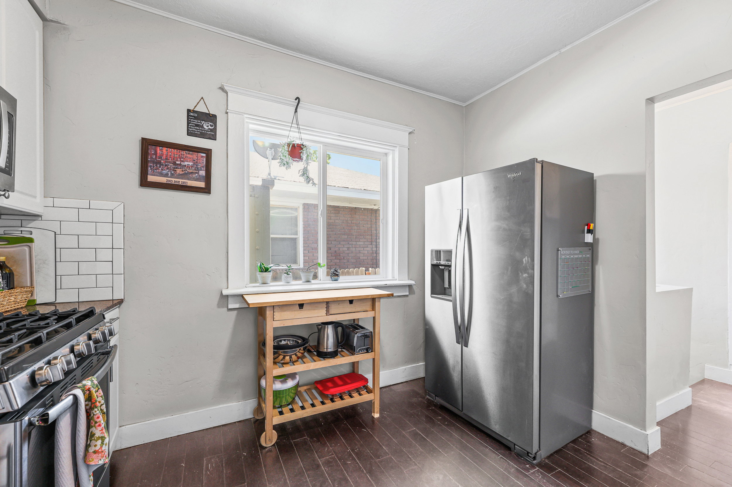 Kitchen featuring wood-finish flooring, white subway tile backsplash, and a stainless steel range with overhead microwave