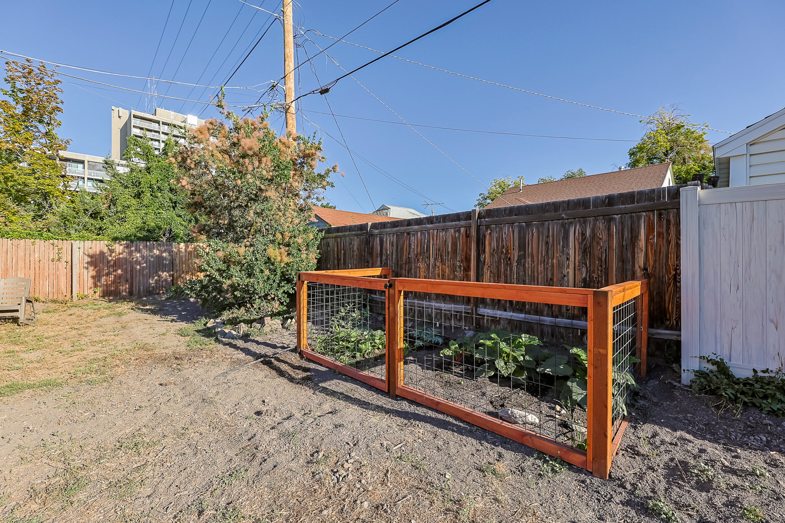 Enclosed garden bed with timber framing and wire mesh, featuring a wood fence, privacy fence, and established greenery