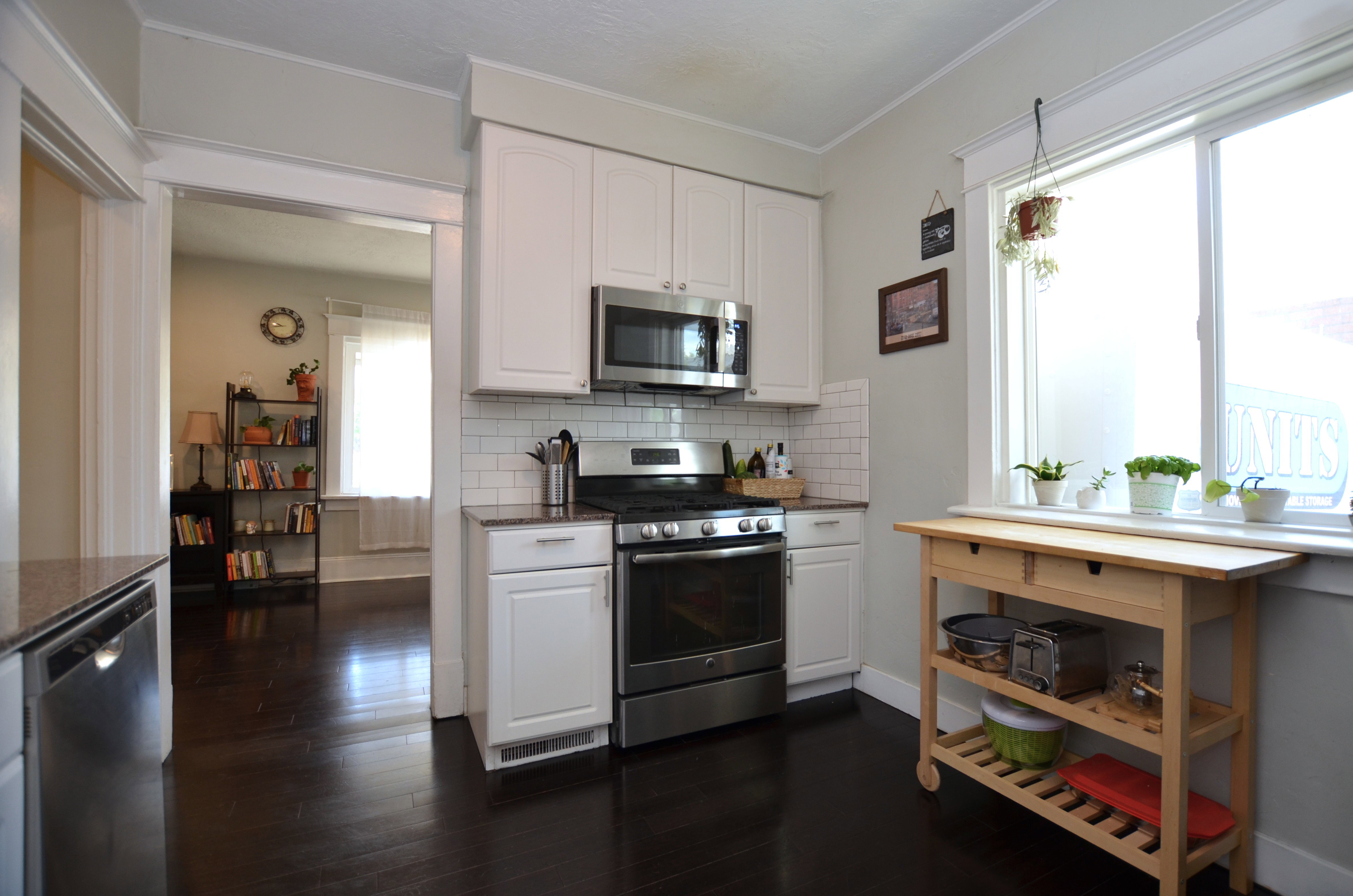 Kitchen featuring white cabinetry, stainless steel appliances, subway tile backsplash, and dark wood-finish flooring