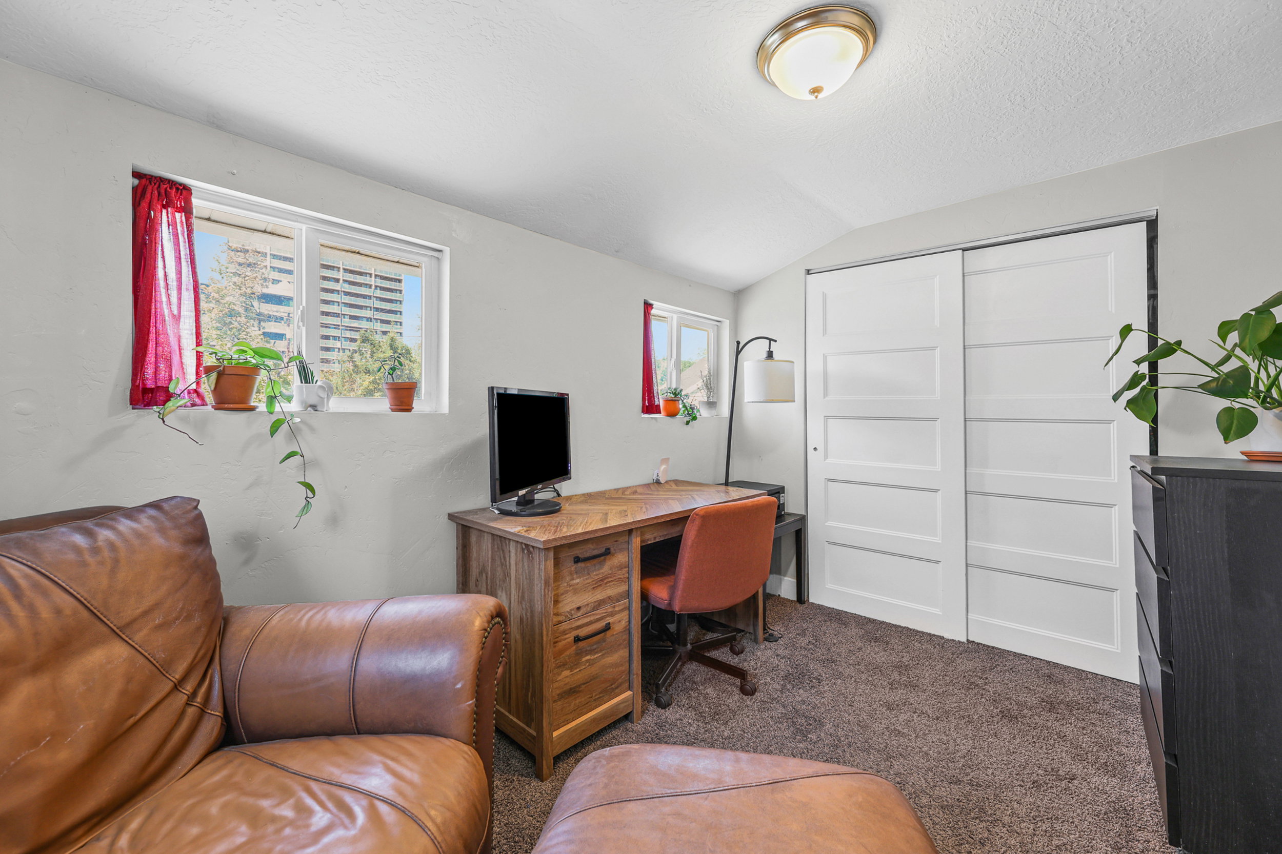 Recessed windows with natural light, textured carpet flooring, bright white walls, and a ceiling-mounted light fixture