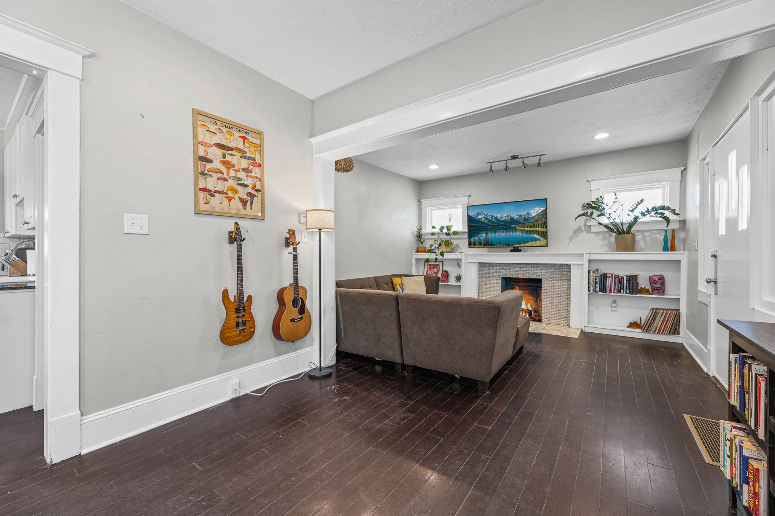 Living area featuring dark wood-finish flooring, a fireplace with a stone surround, and built-in shelving