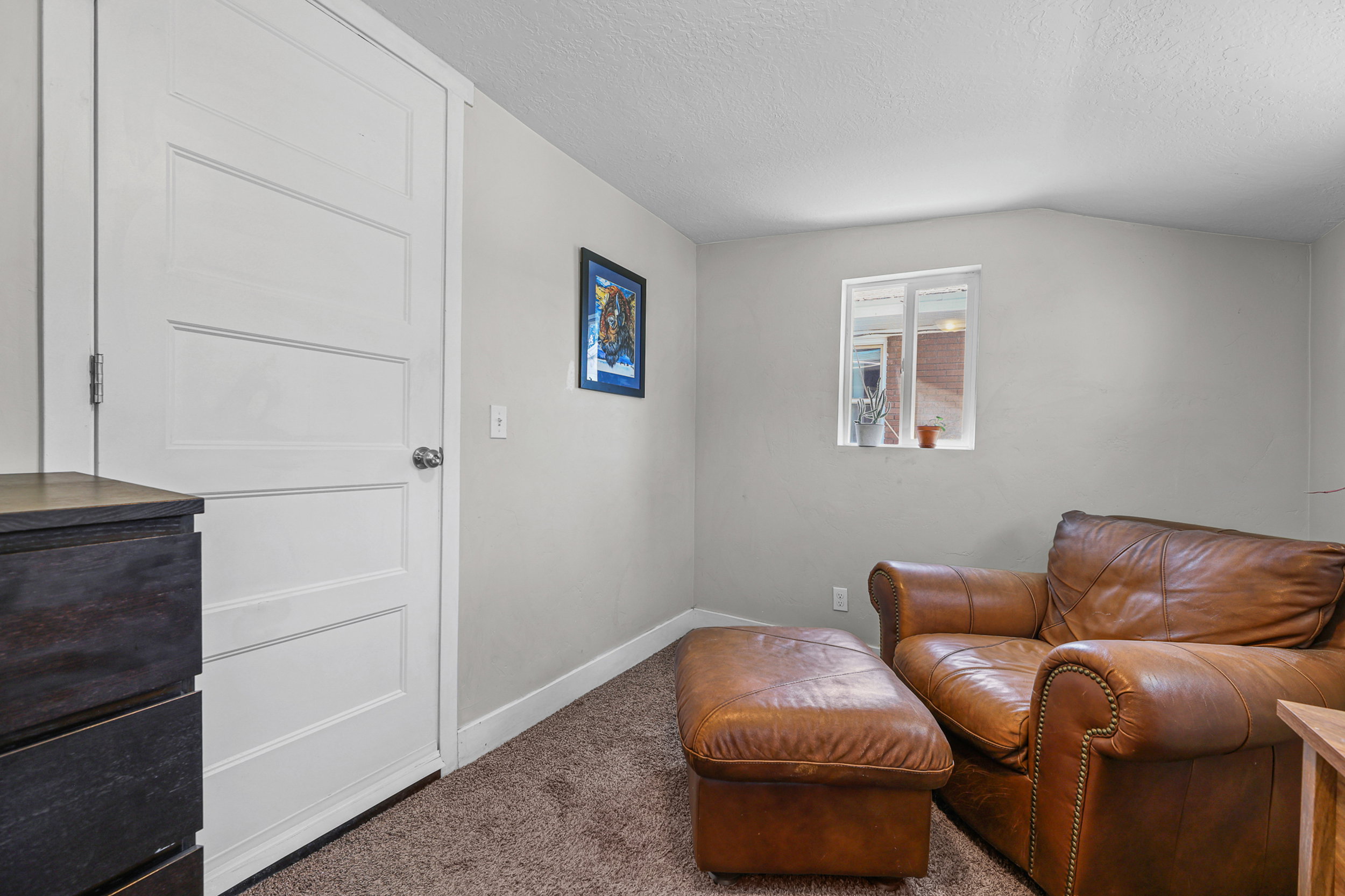 Inviting room featuring a single window, white trim, light gray walls, and brown carpet flooring