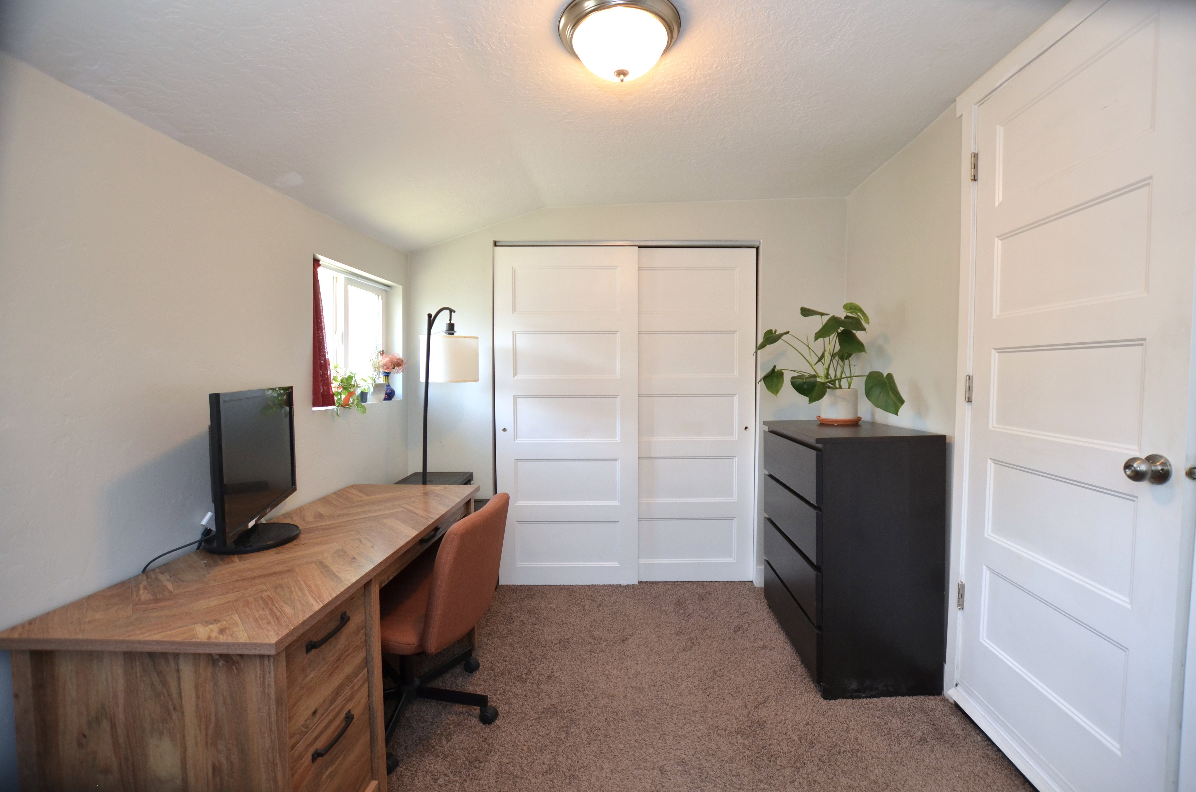 Recessed window with natural light, textured ceiling, brown carpeting, and a four-panel sliding closet door