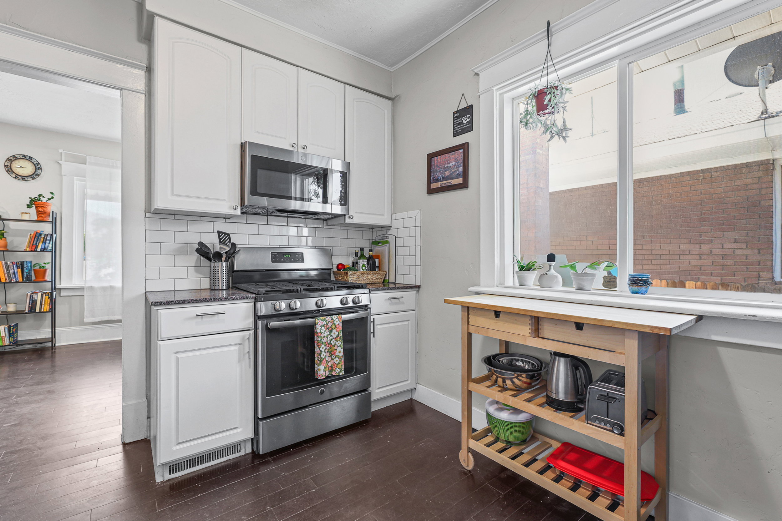 Kitchen featuring white shaker-style cabinetry, a subway tile backsplash, and dark wood-finish flooring