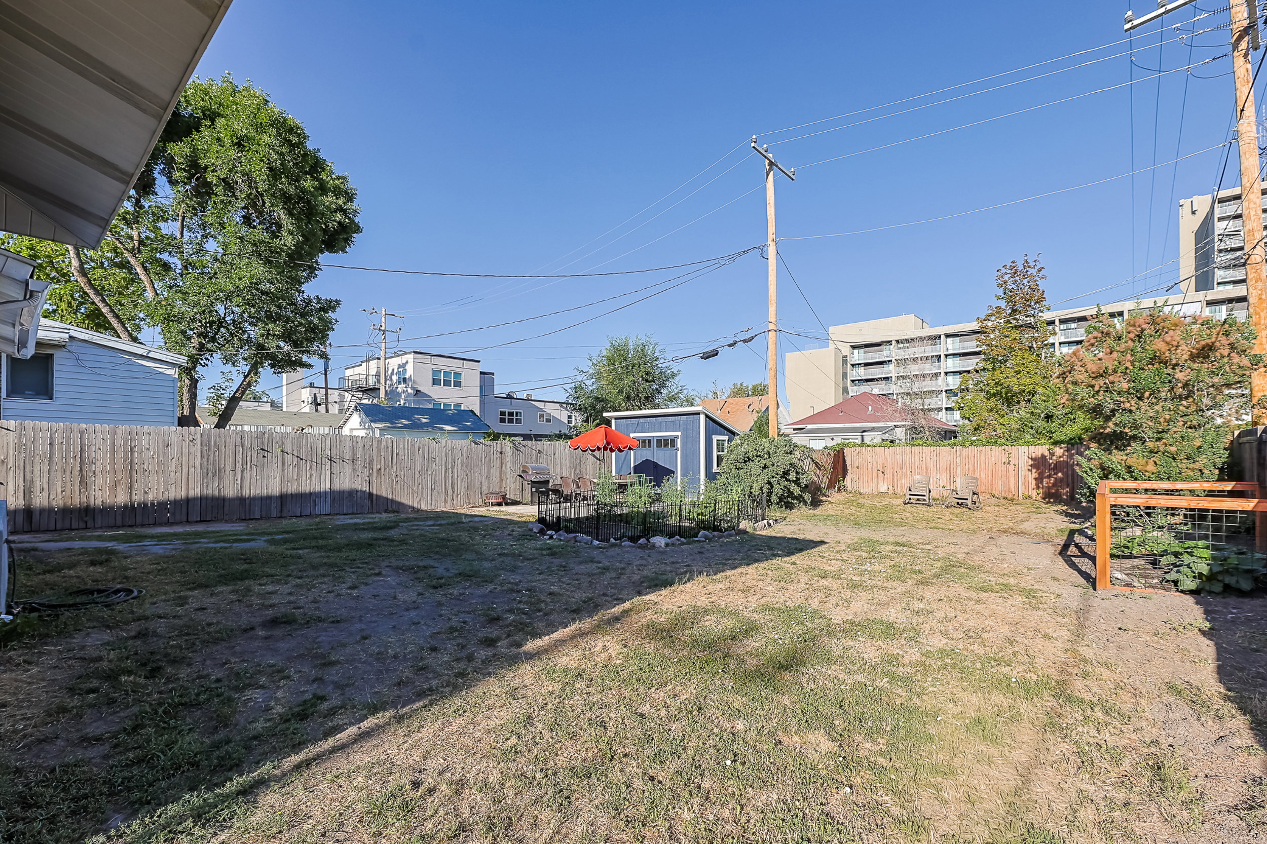 Expansive backyard featuring a full privacy fence, a detached storage shed, and a raised garden bed