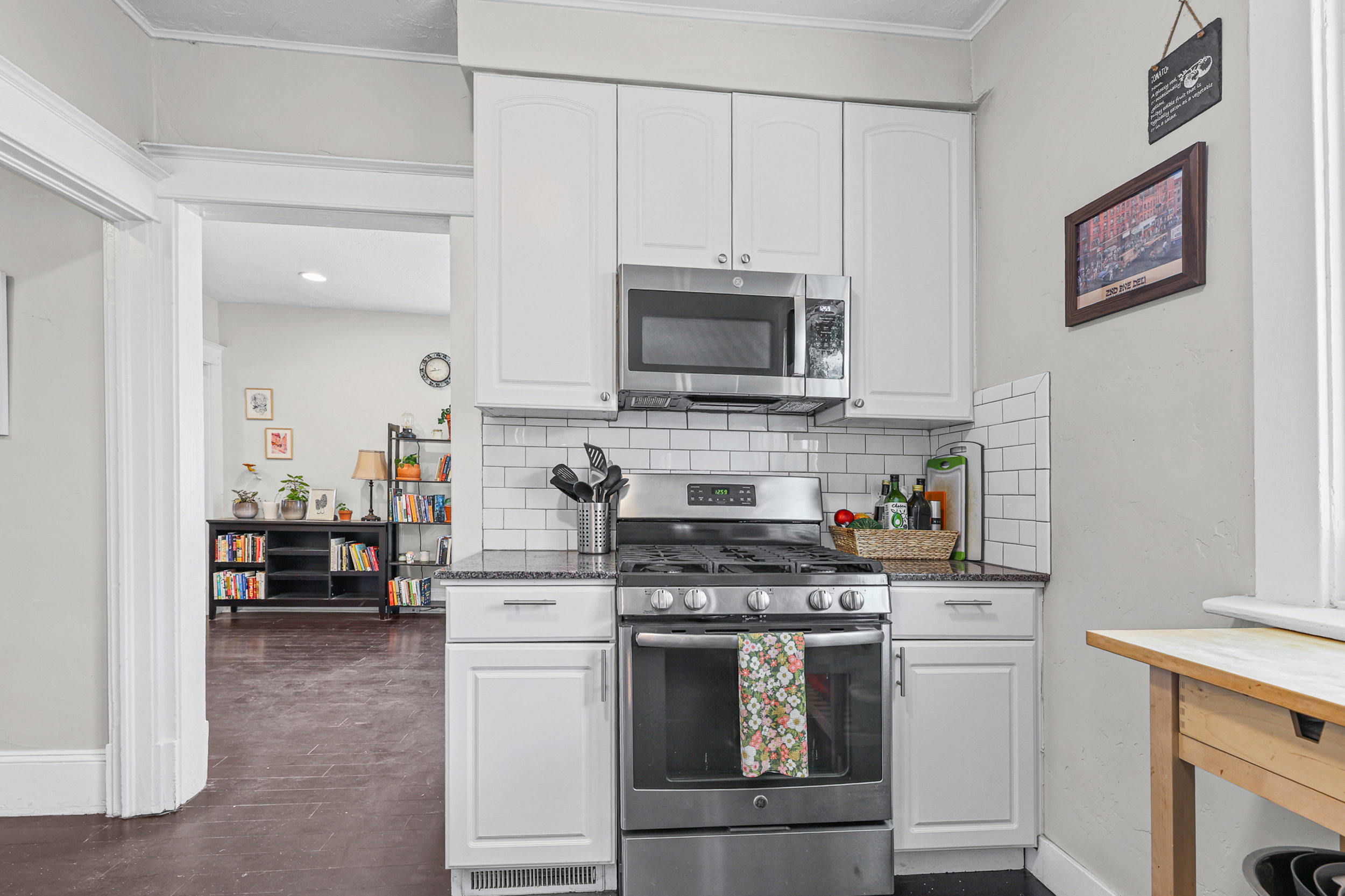 Kitchen featuring white cabinetry, subway tile backsplash, dark countertops, stainless steel appliances, and a gas range
