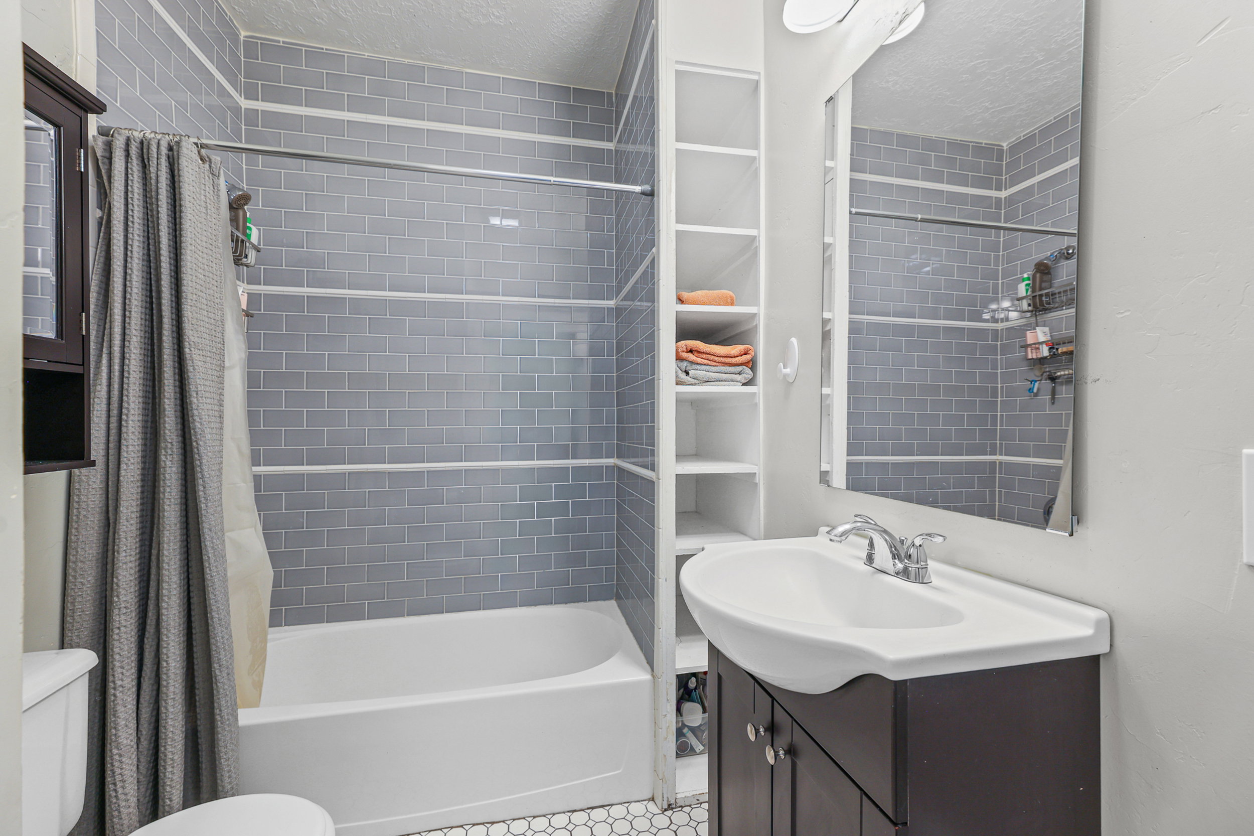 Bathroom featuring a subway-tiled shower surround, a white soaking tub, and hexagon-tiled flooring