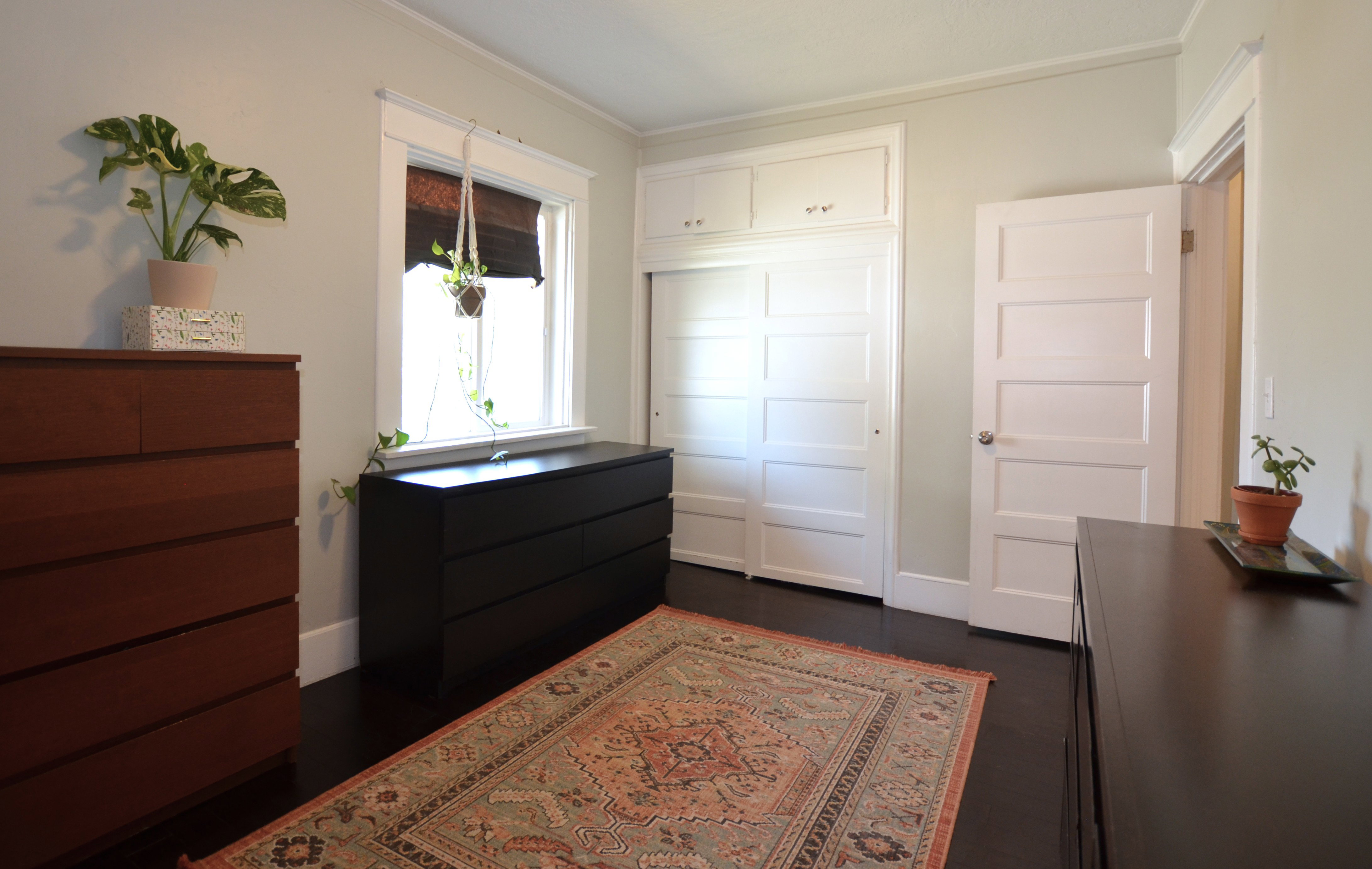Dark wood-finish flooring with white baseboards and light-colored walls