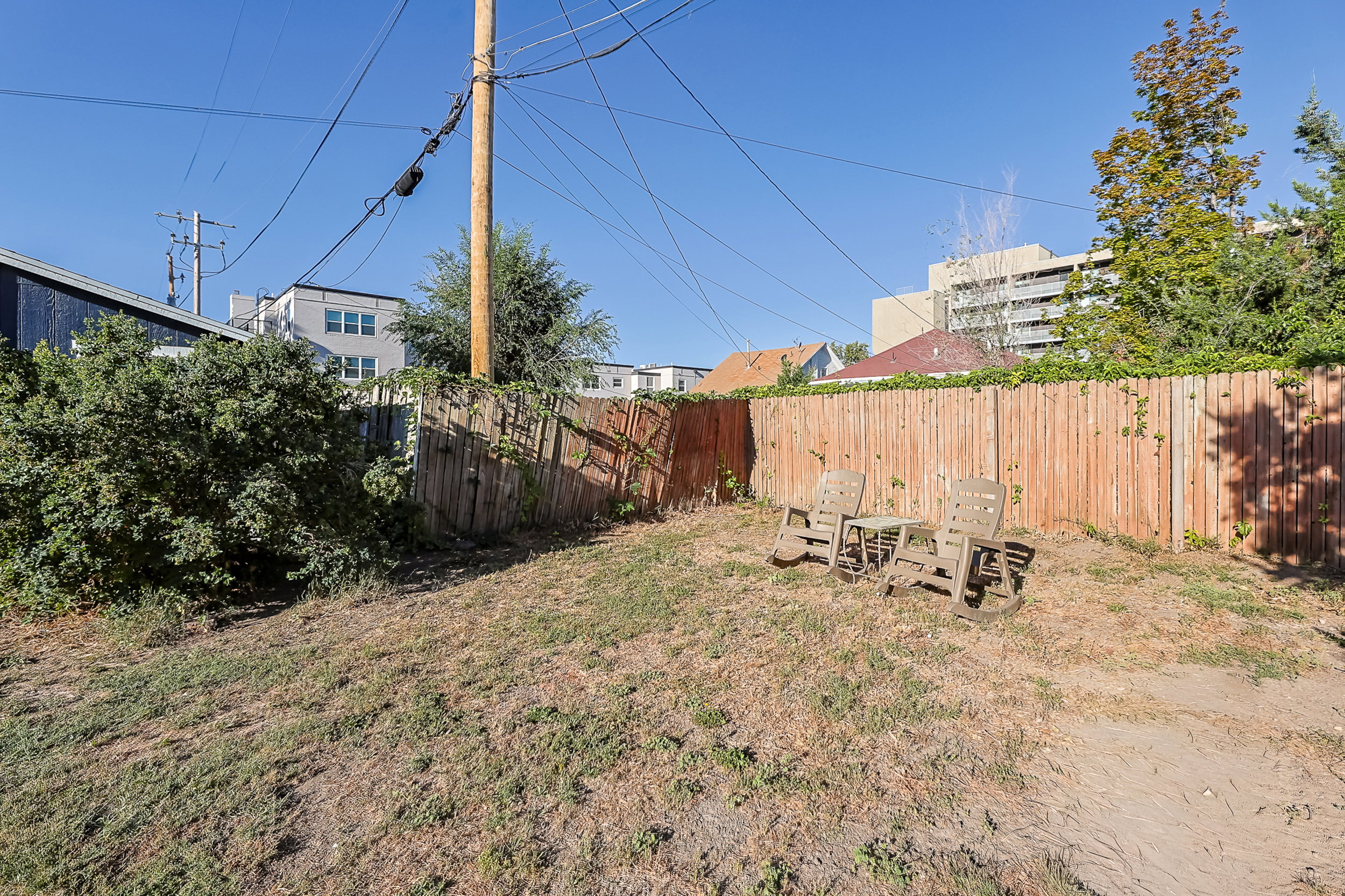 Expansive outdoor area featuring a wood privacy fence and mature perimeter landscaping