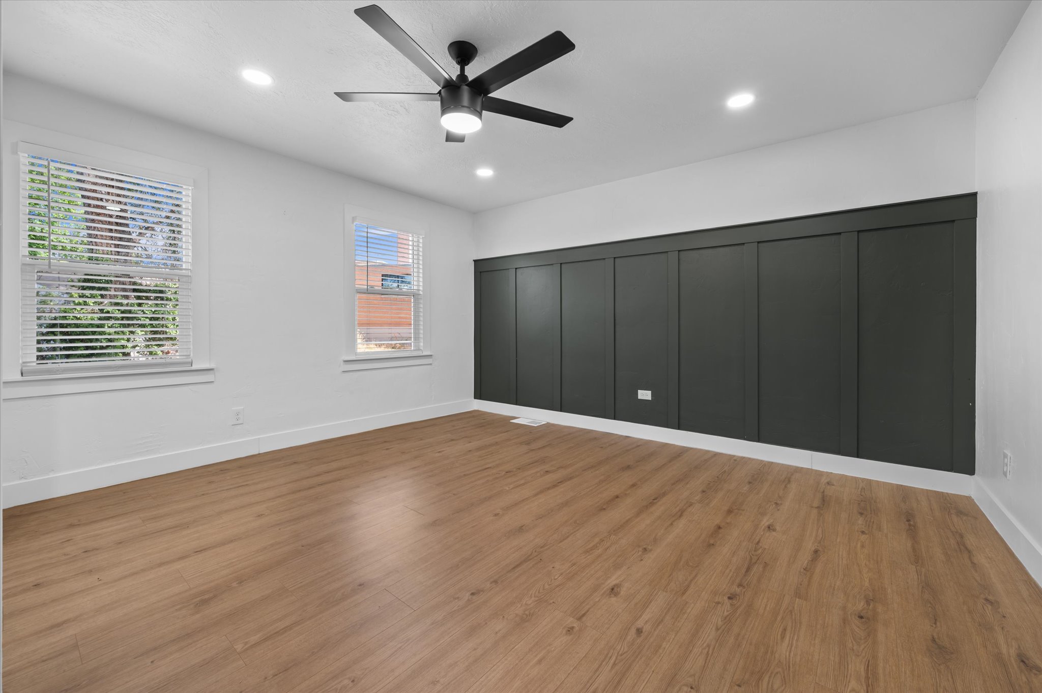 Spacious room with wood-finish flooring, recessed lighting, and a modern ceiling fan