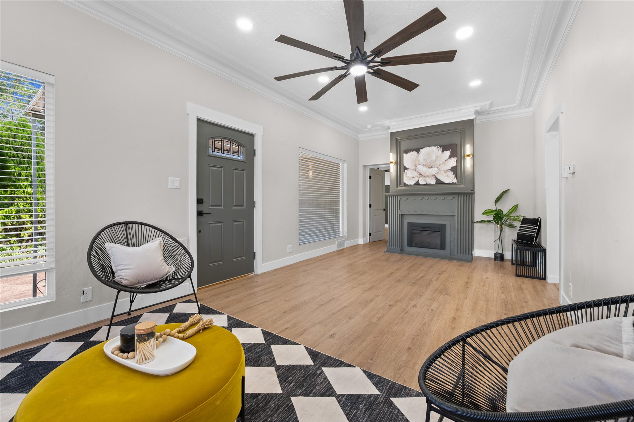 Spacious living area featuring wood-finish flooring, a contemporary ceiling fan with integrated lighting, and crown molding