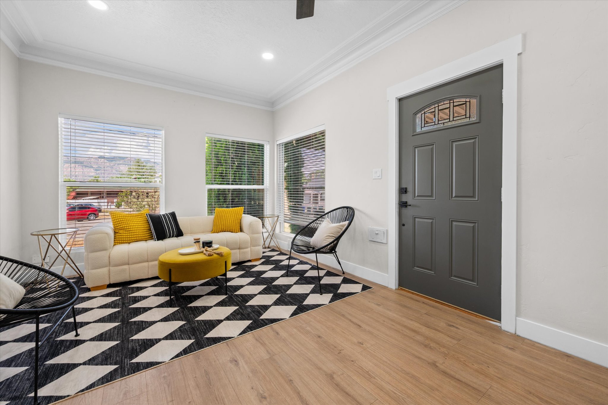 Entryway and living area featuring wood-finish flooring, a paneled entry door with decorative glass insert, multiple large windows with blinds, and recessed lighting