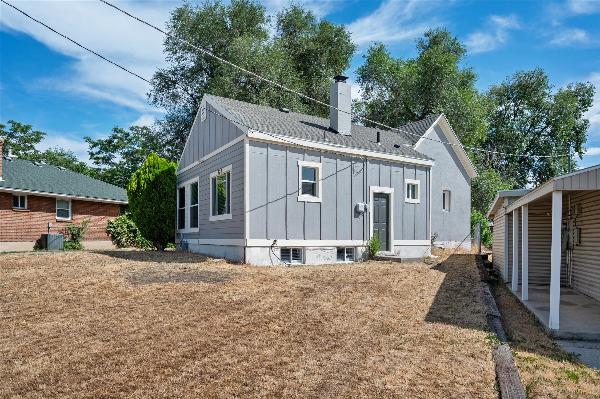Exterior featuring light blue siding, a dark gray roof, and a gray-painted chimney
