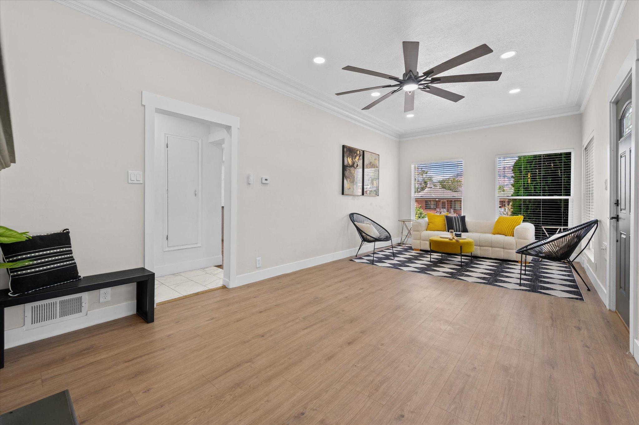 Open-concept living area featuring wood-finish flooring, a contemporary ceiling fan, recessed lighting, and crown molding