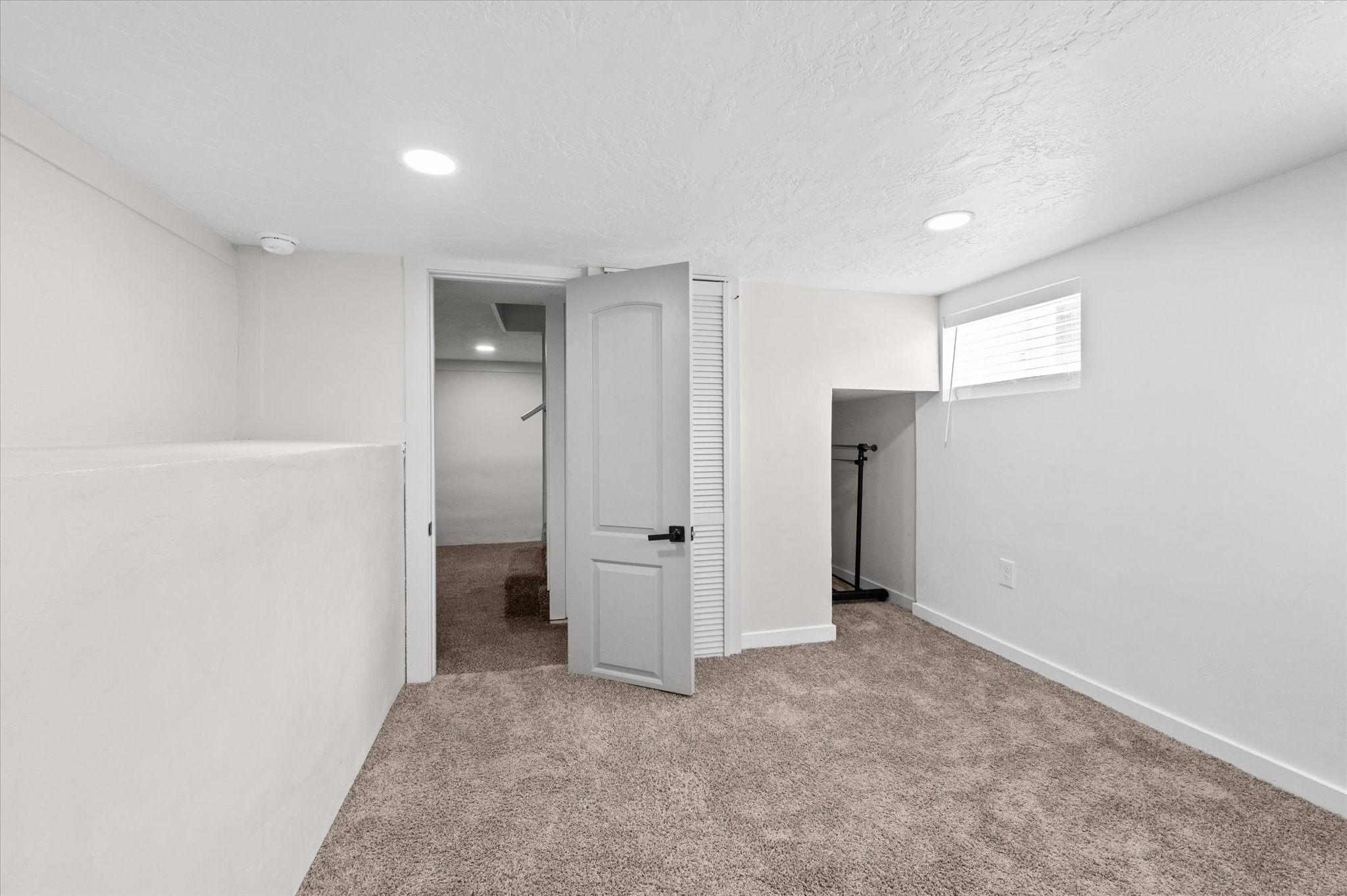 Carpeted room with a white door and a window