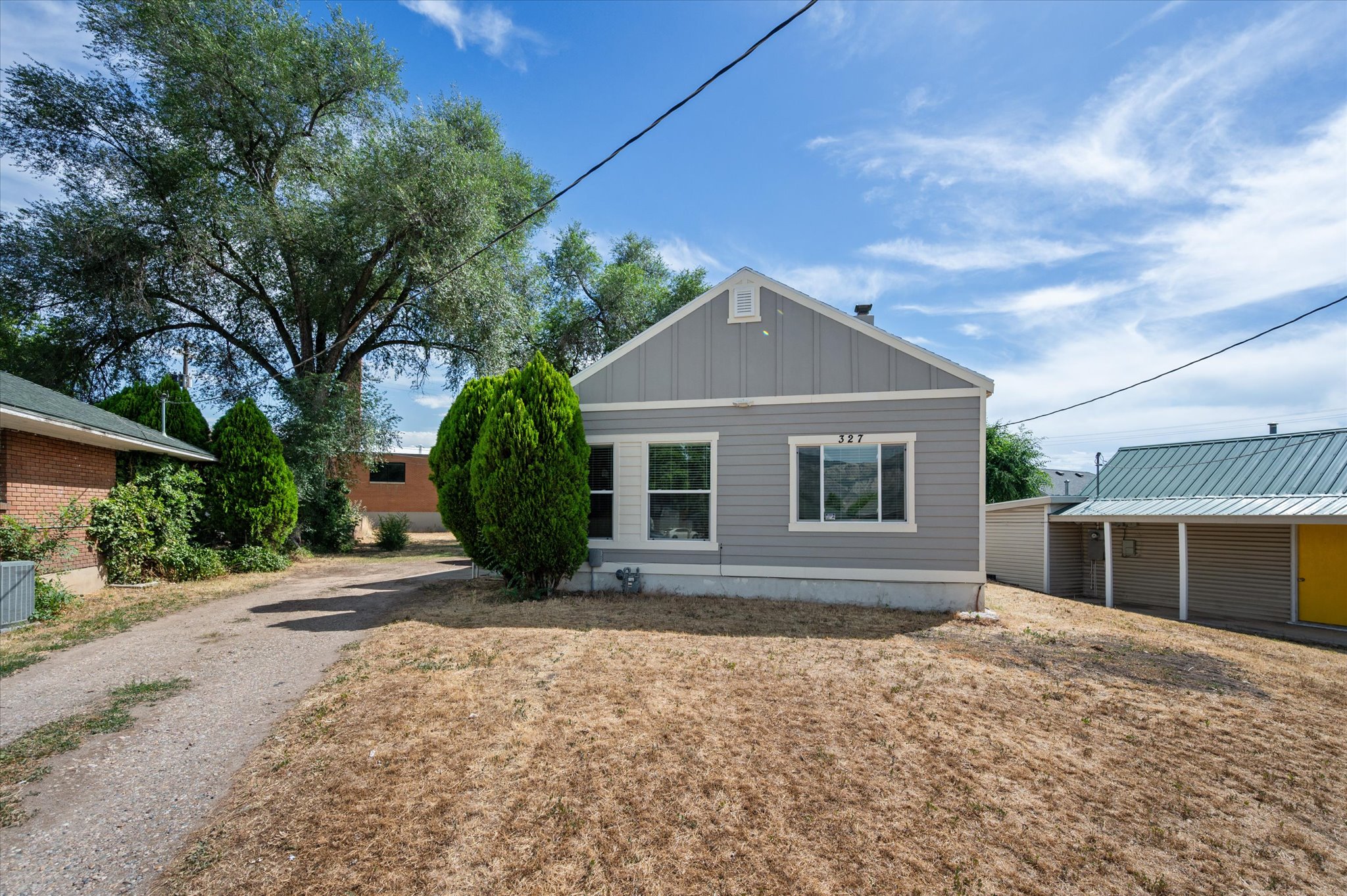 Gray siding exterior with white trim, featuring a gable roofline and prominent front windows