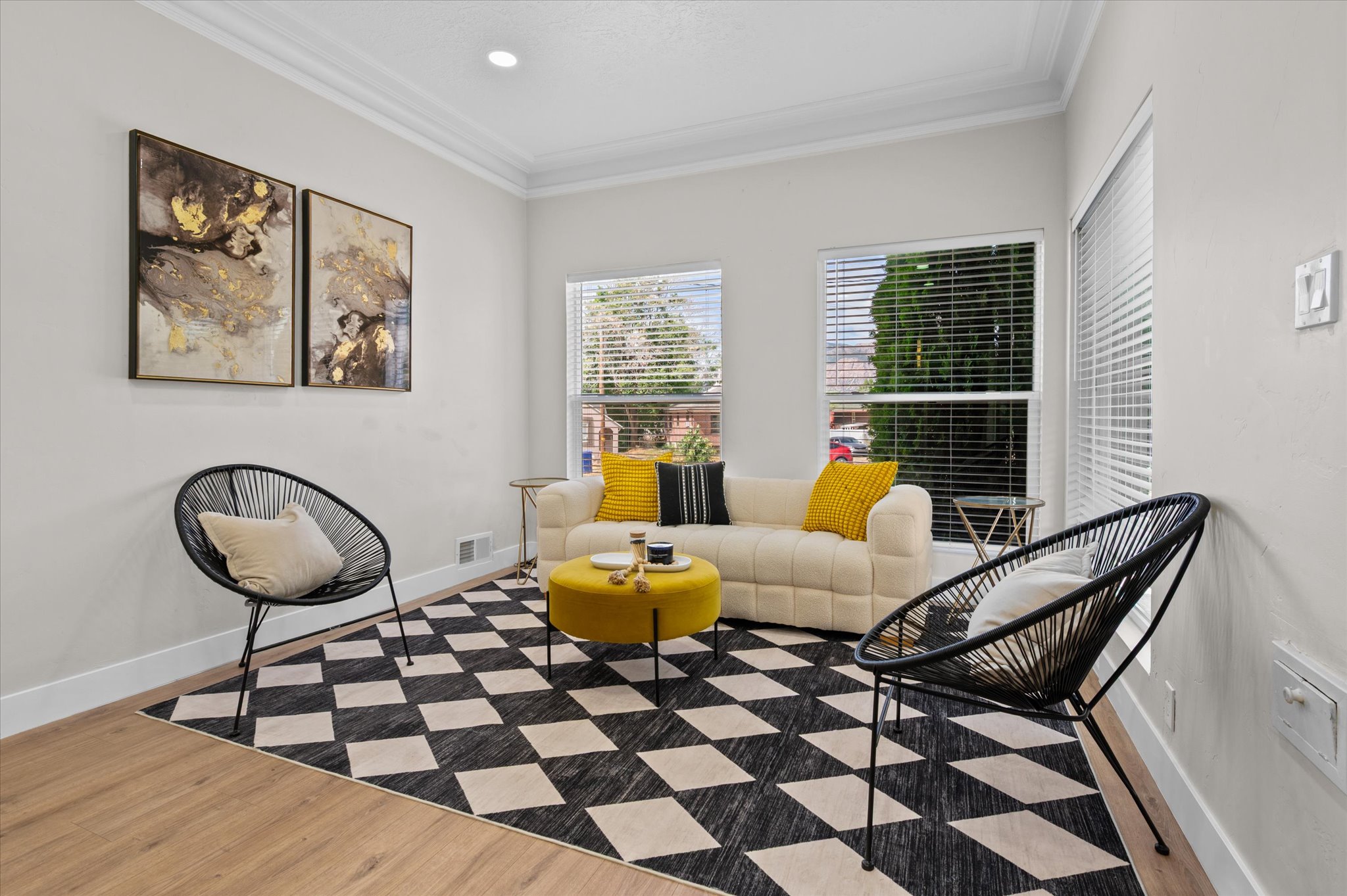 Living area featuring wood-finish flooring, white baseboards, and crown molding