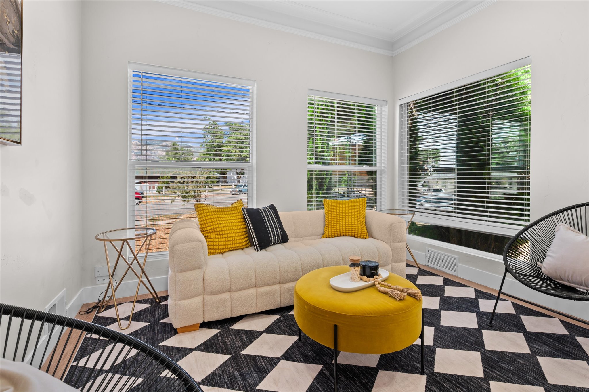 Bright living space featuring multiple windows with blinds, crown molding, and wood-finish flooring