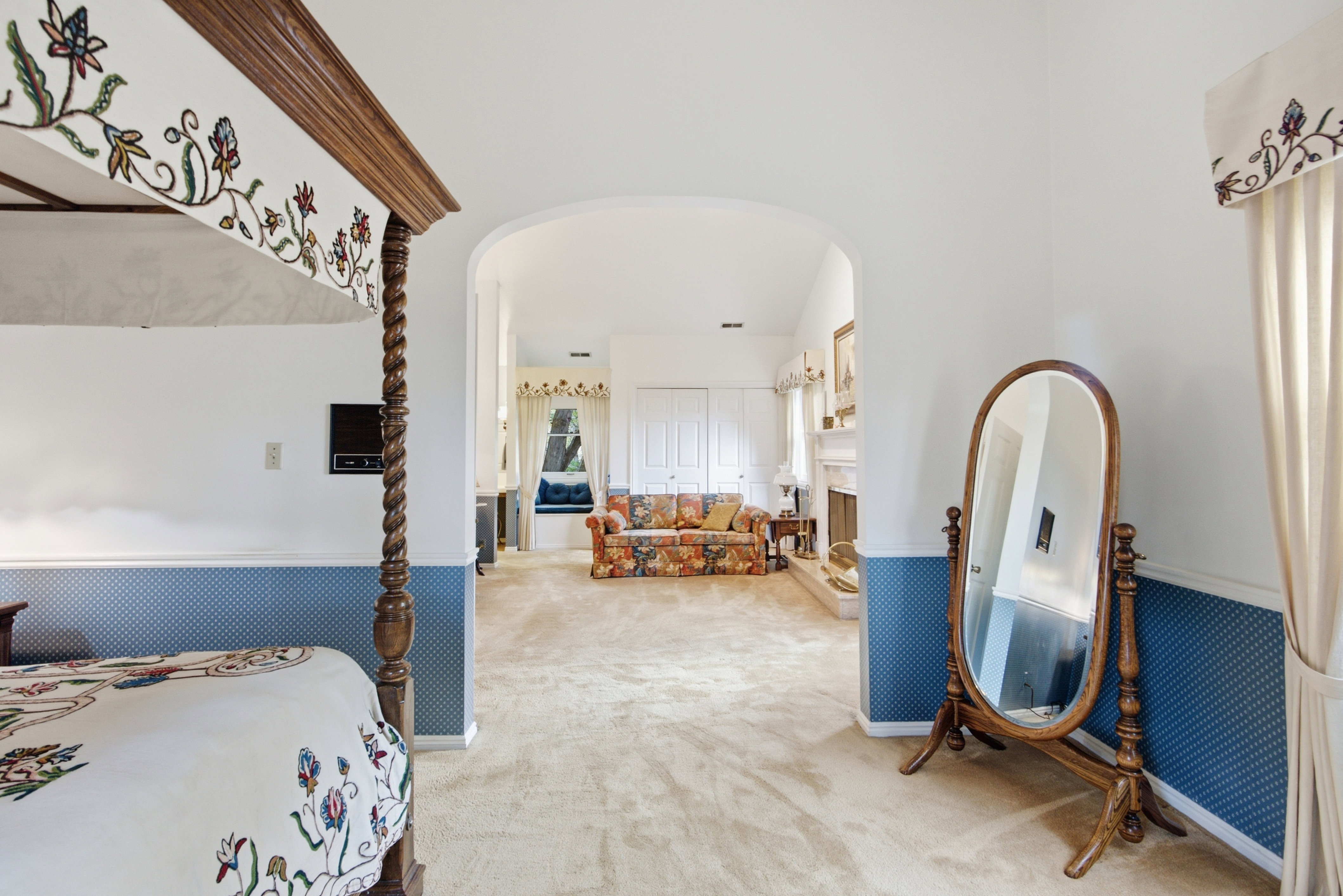 Arched doorway leading to a carpeted room with a fireplace and window seating
