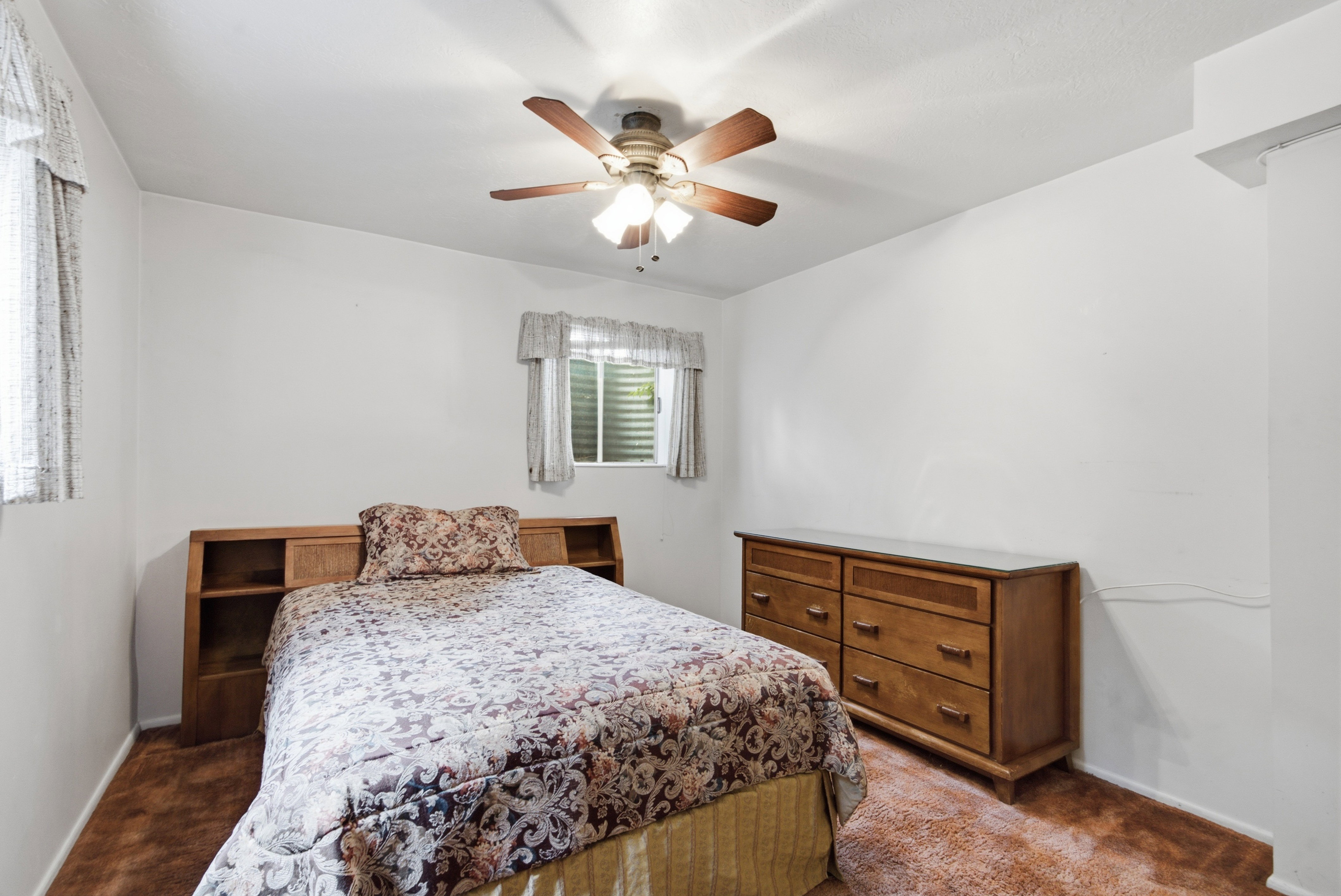 Bedroom featuring a ceiling fan with integrated lighting, a window with horizontal blinds, and neutral wall tones