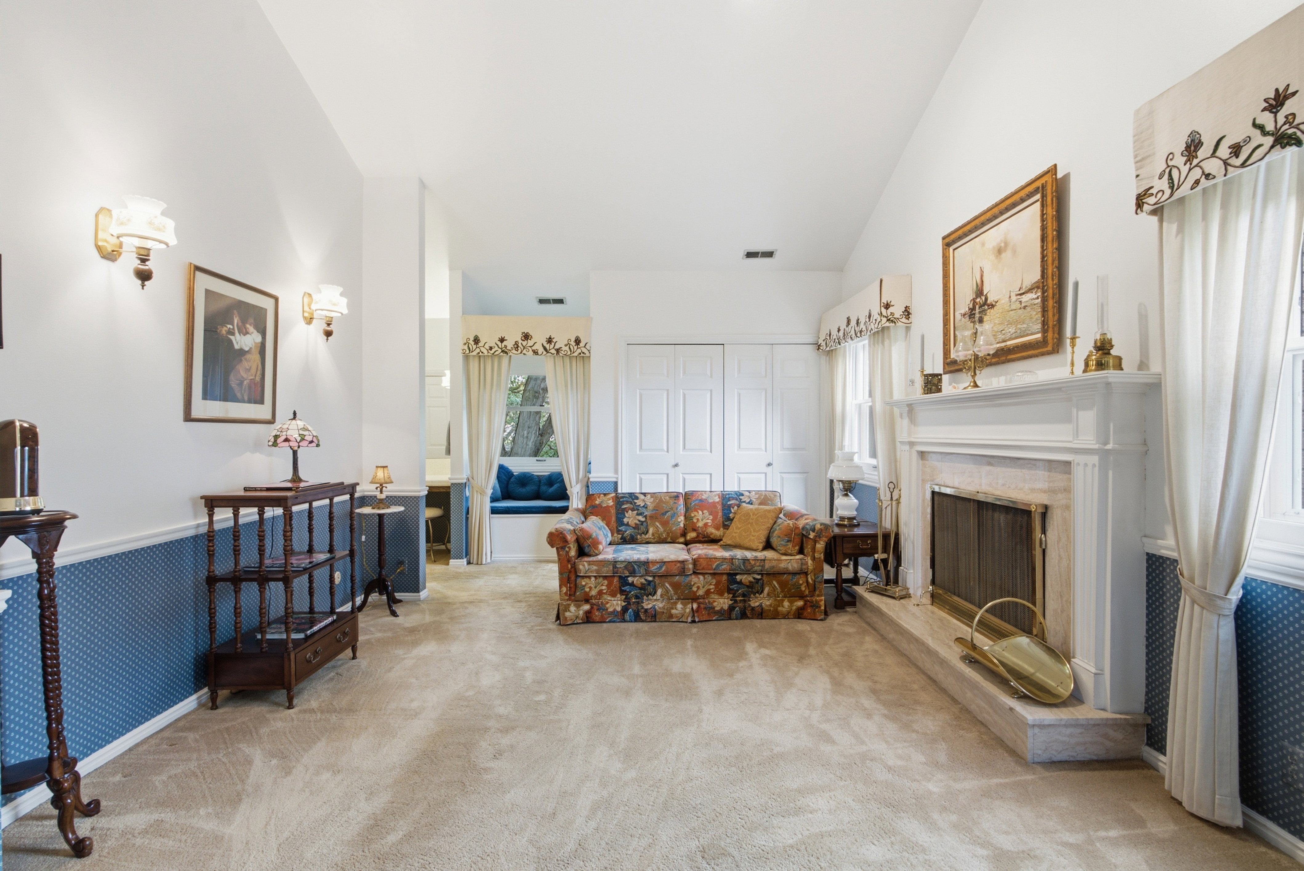 Spacious living area featuring a prominent fireplace with a substantial hearth, vaulted ceilings, and a built-in window seat