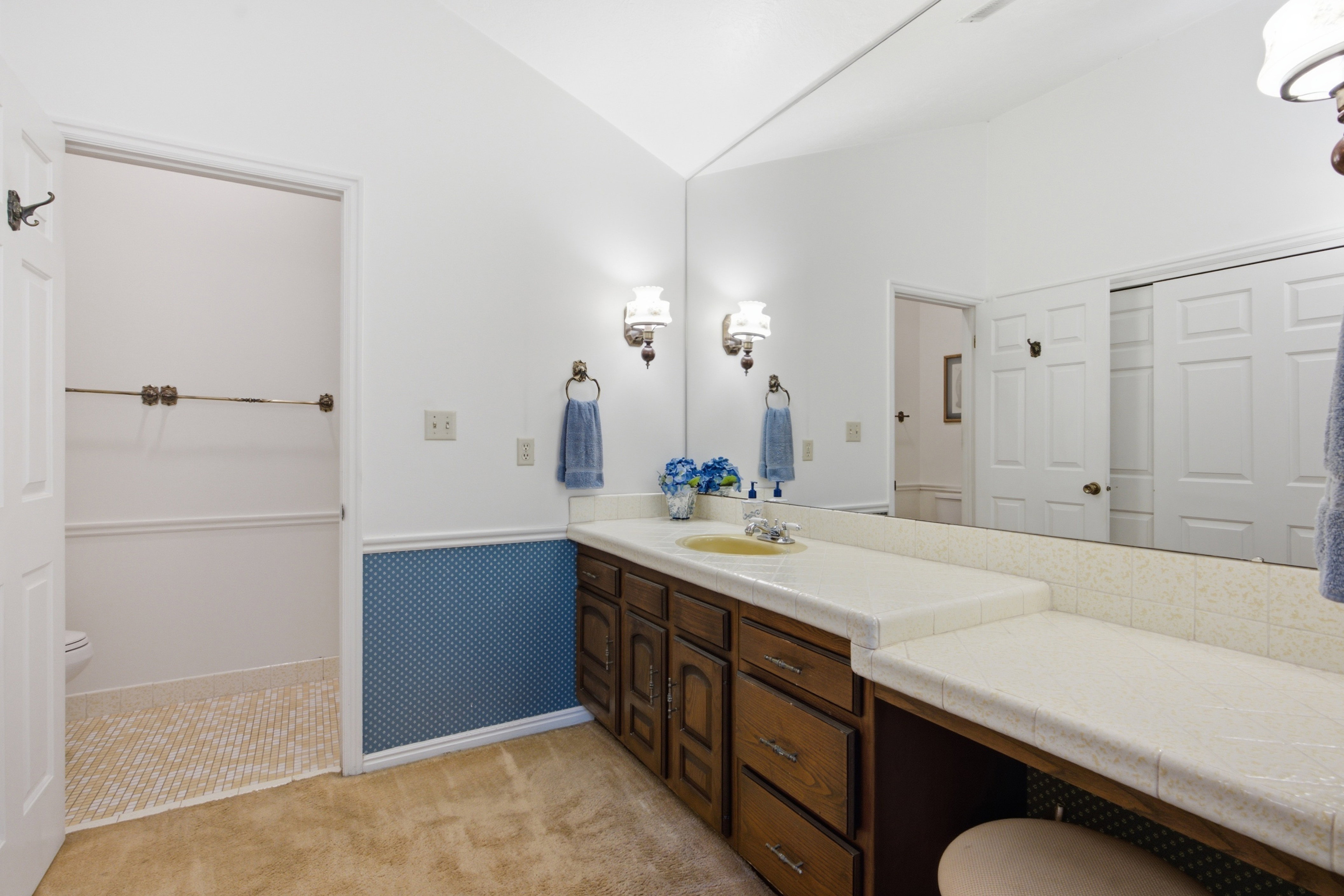 Bathroom vanity featuring a tile countertop, integrated sink, and wood cabinetry with storage