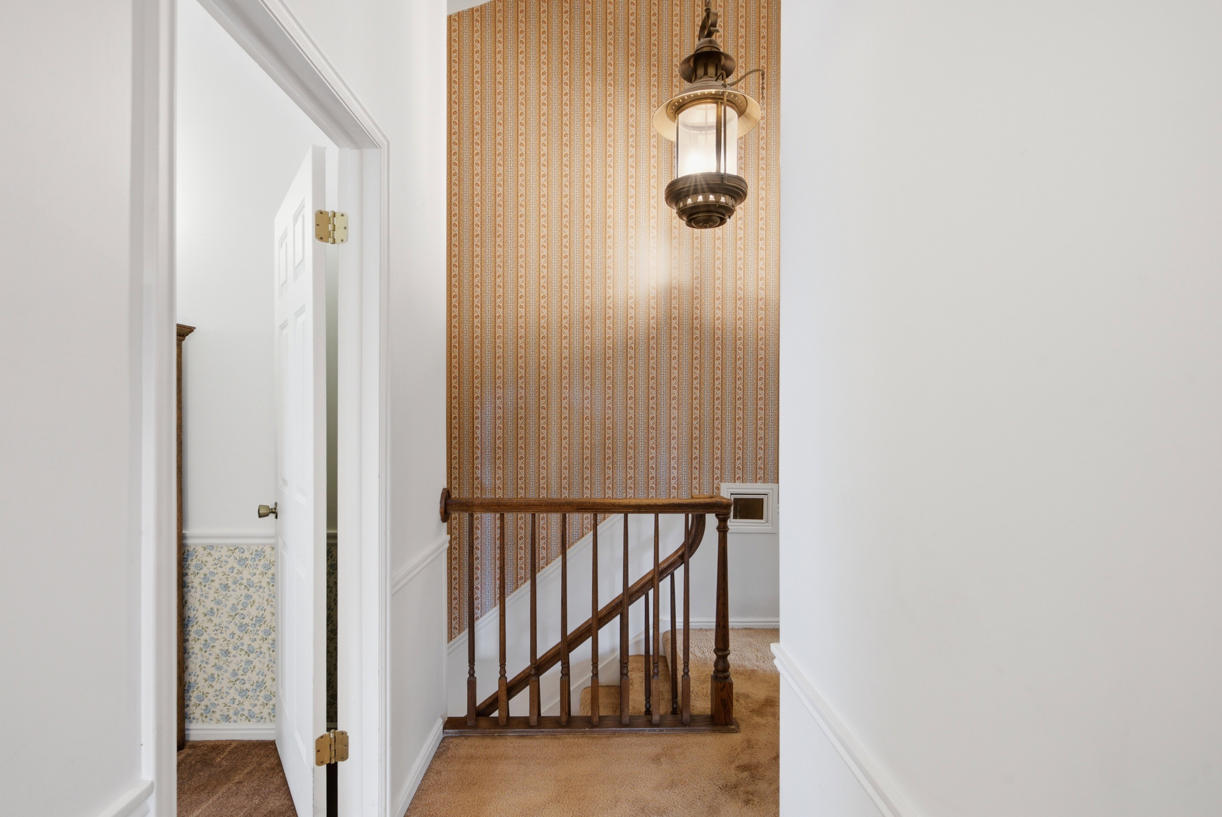 Staircase with wood balusters and a lantern-style pendant light fixture